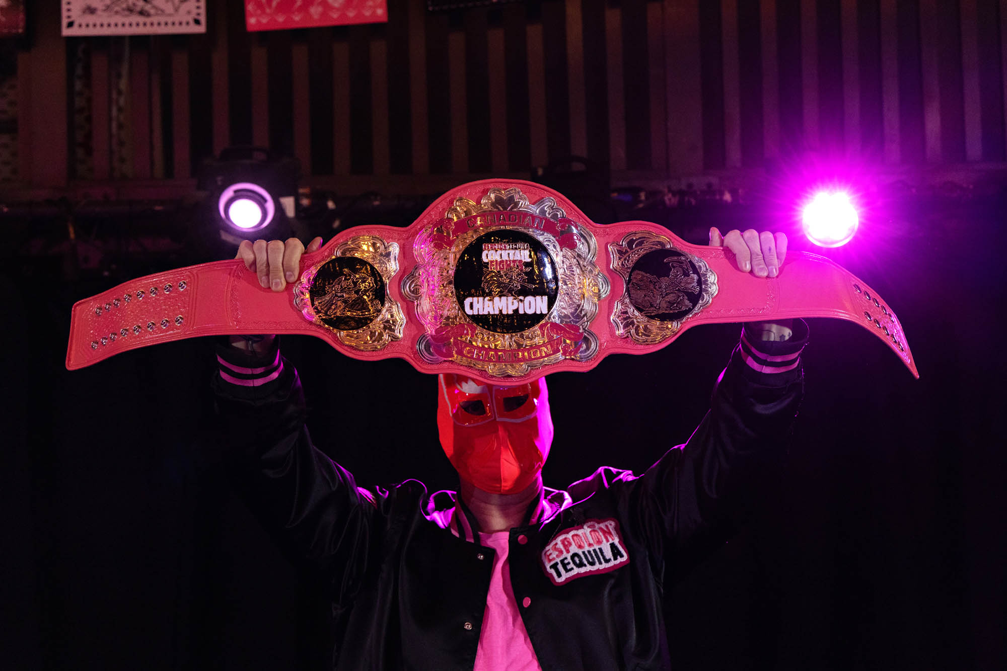 Espolòn Cocktail Fights championship belt held above the winning competitor