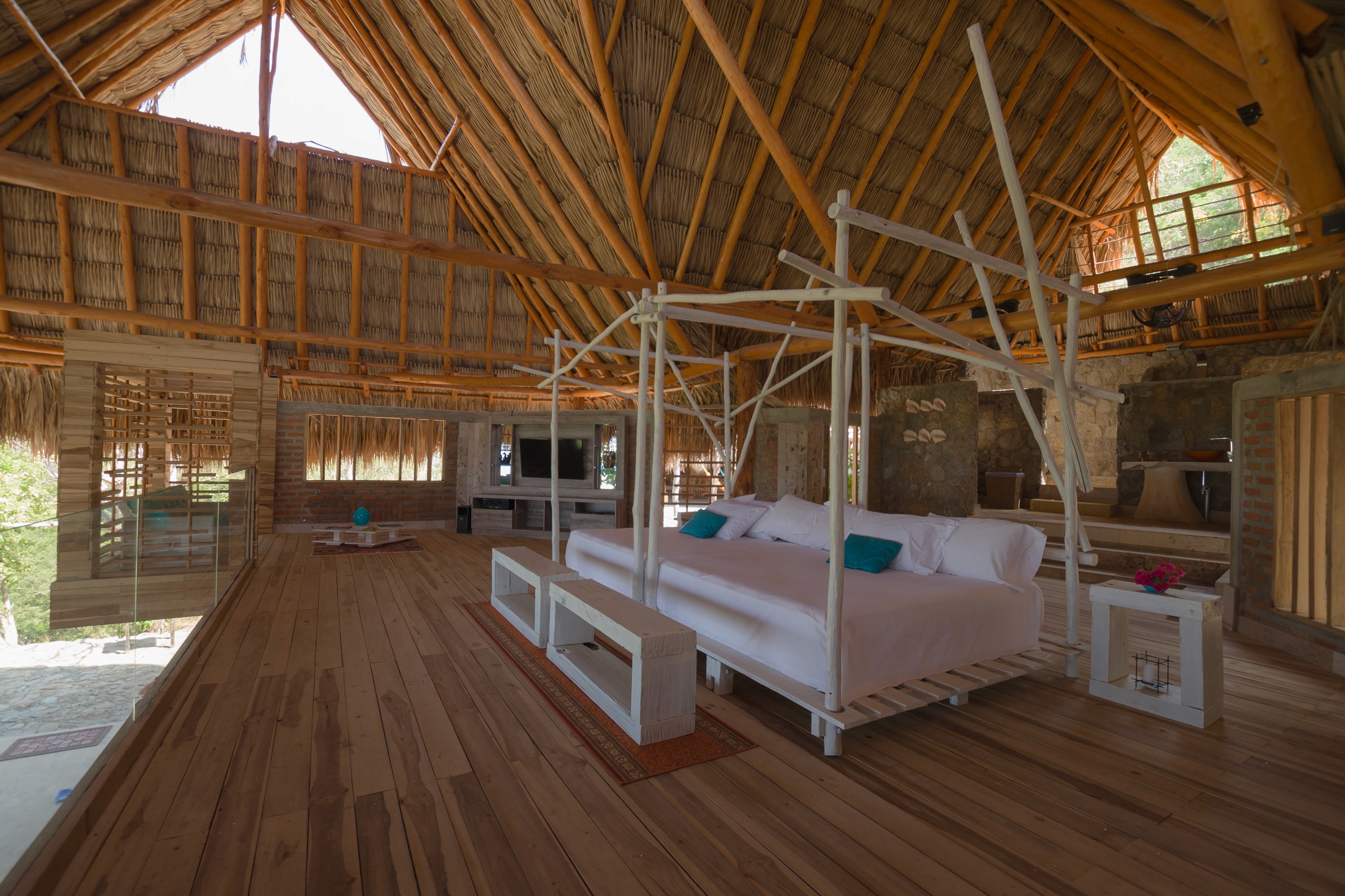 View from patio into the suite, surrounded by lush greenery, queen bed framed inside with neutral-toned decor.