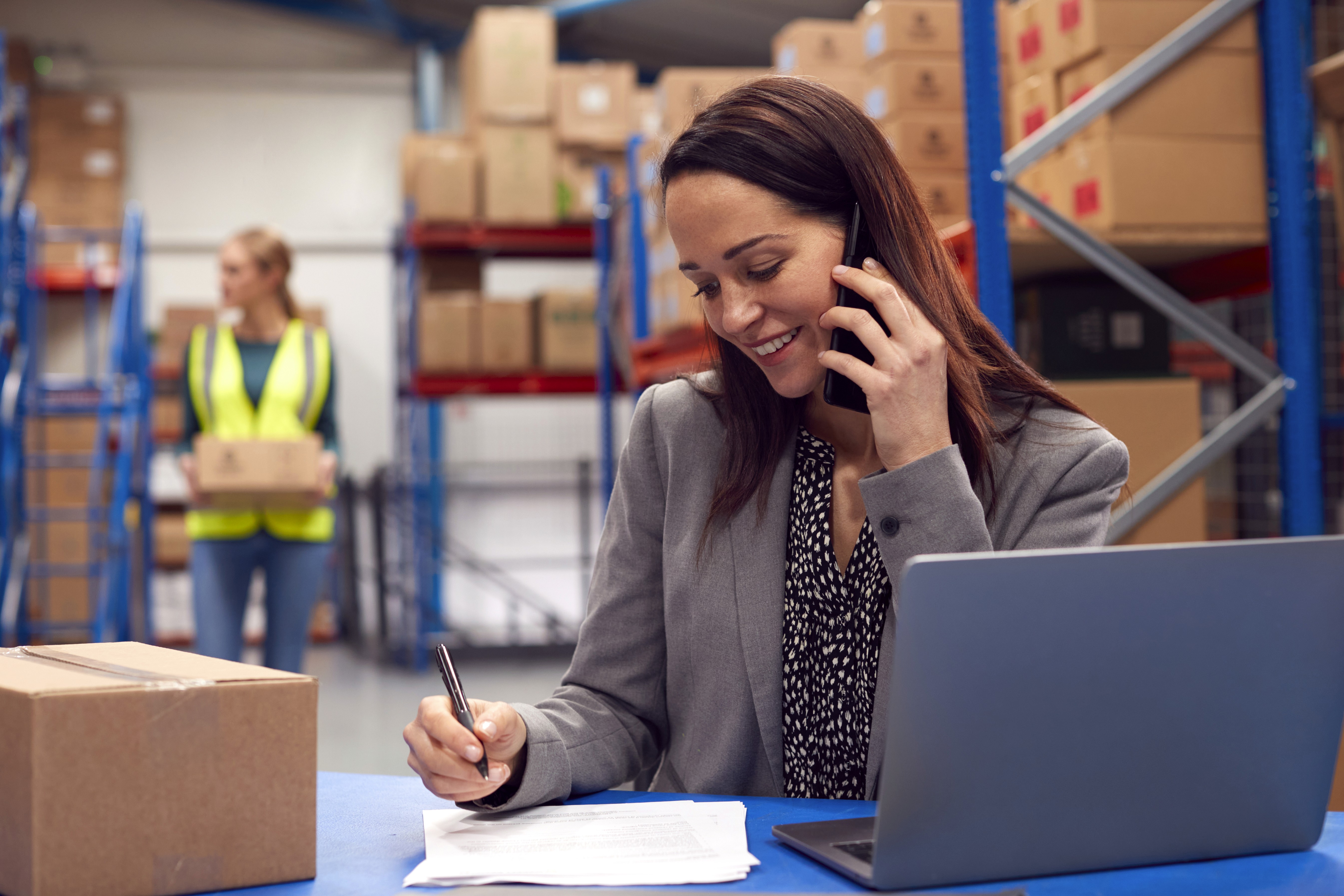 Lady sitting next to a laptop while making a phone call