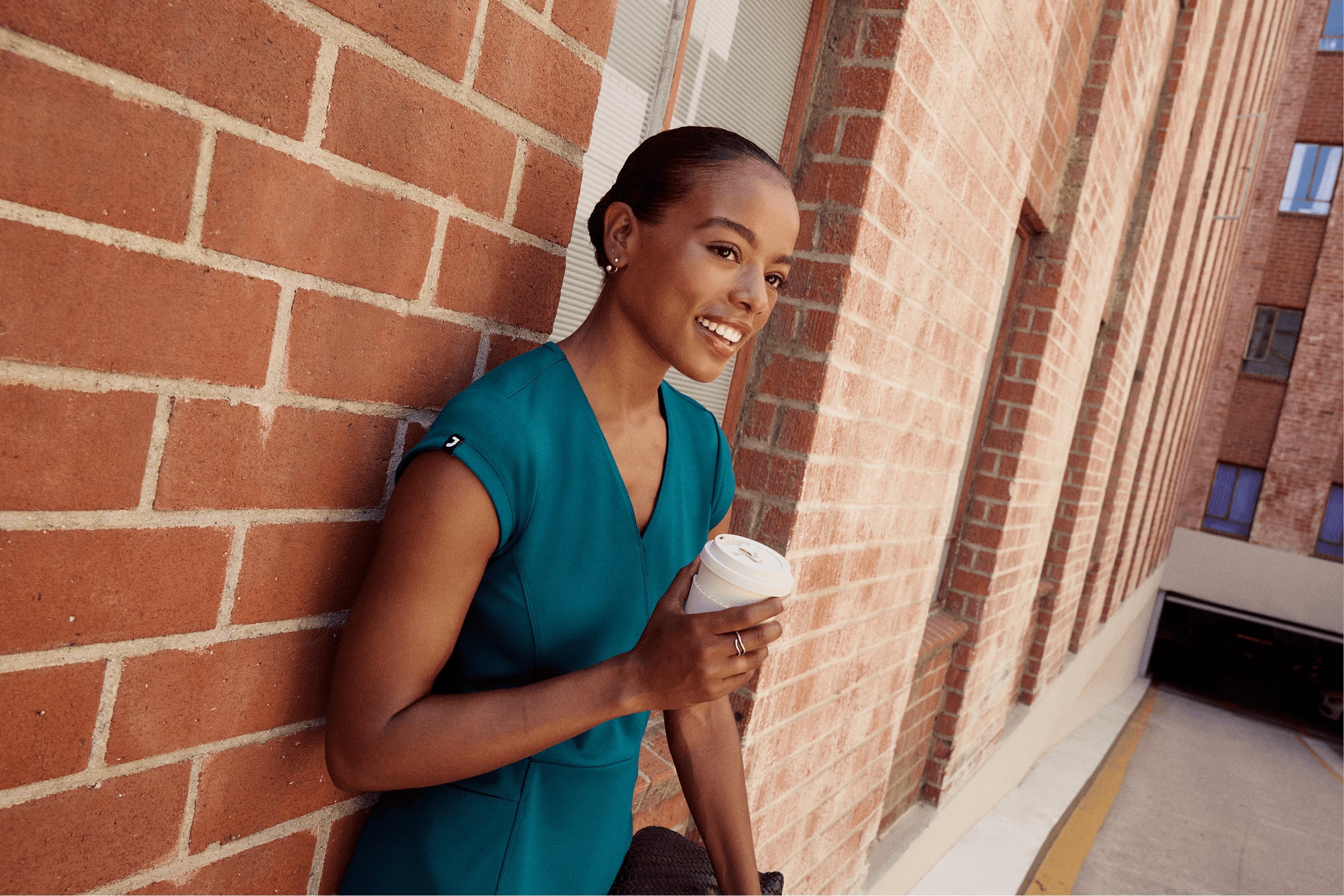 A child in a hat plaiyng with a dinosaur activity outside, smiling at it.