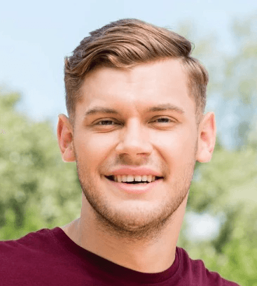 A young man with dark hair and a beard smiles slightly at the camera.