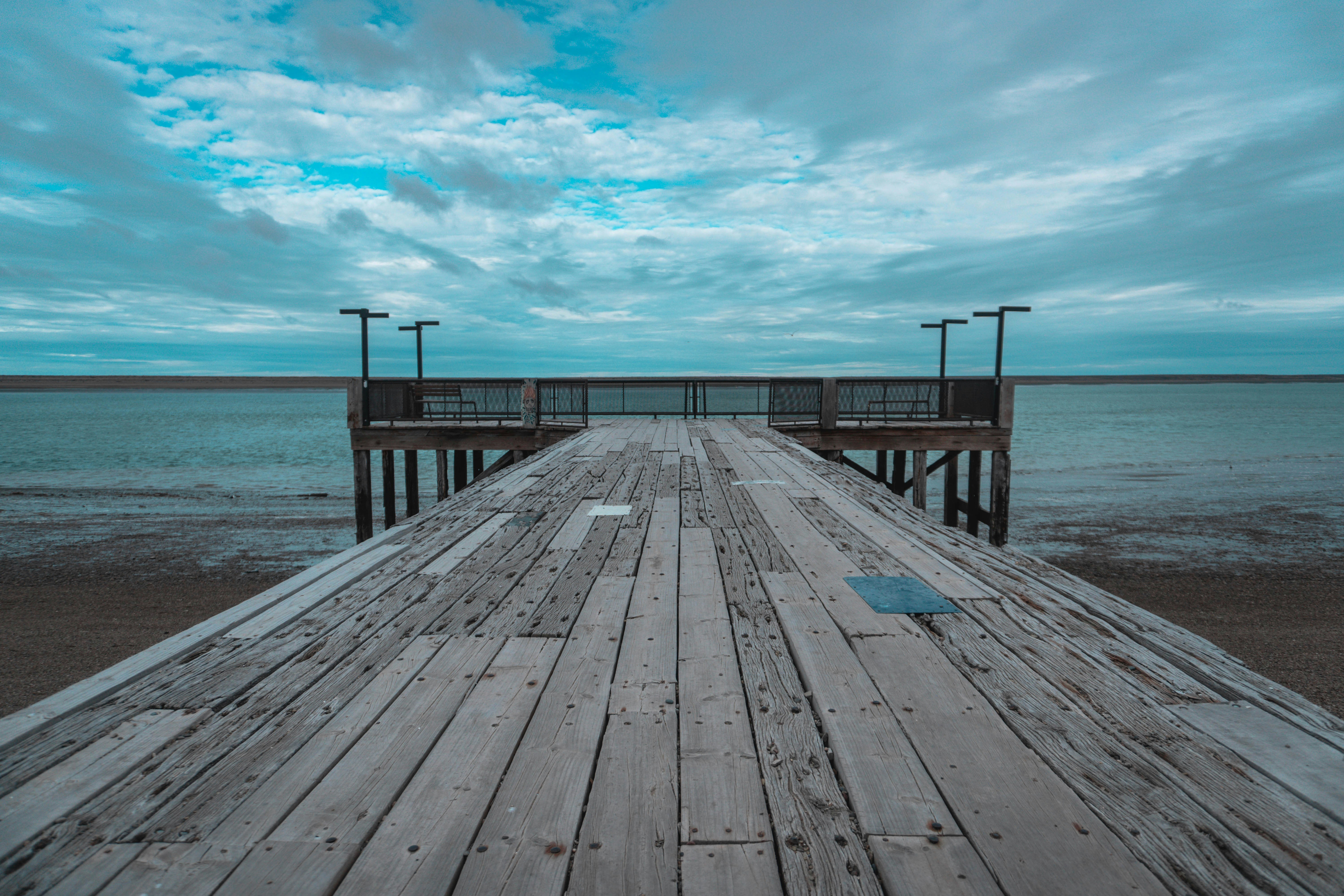 a long wooden pier with a blue sky in the background