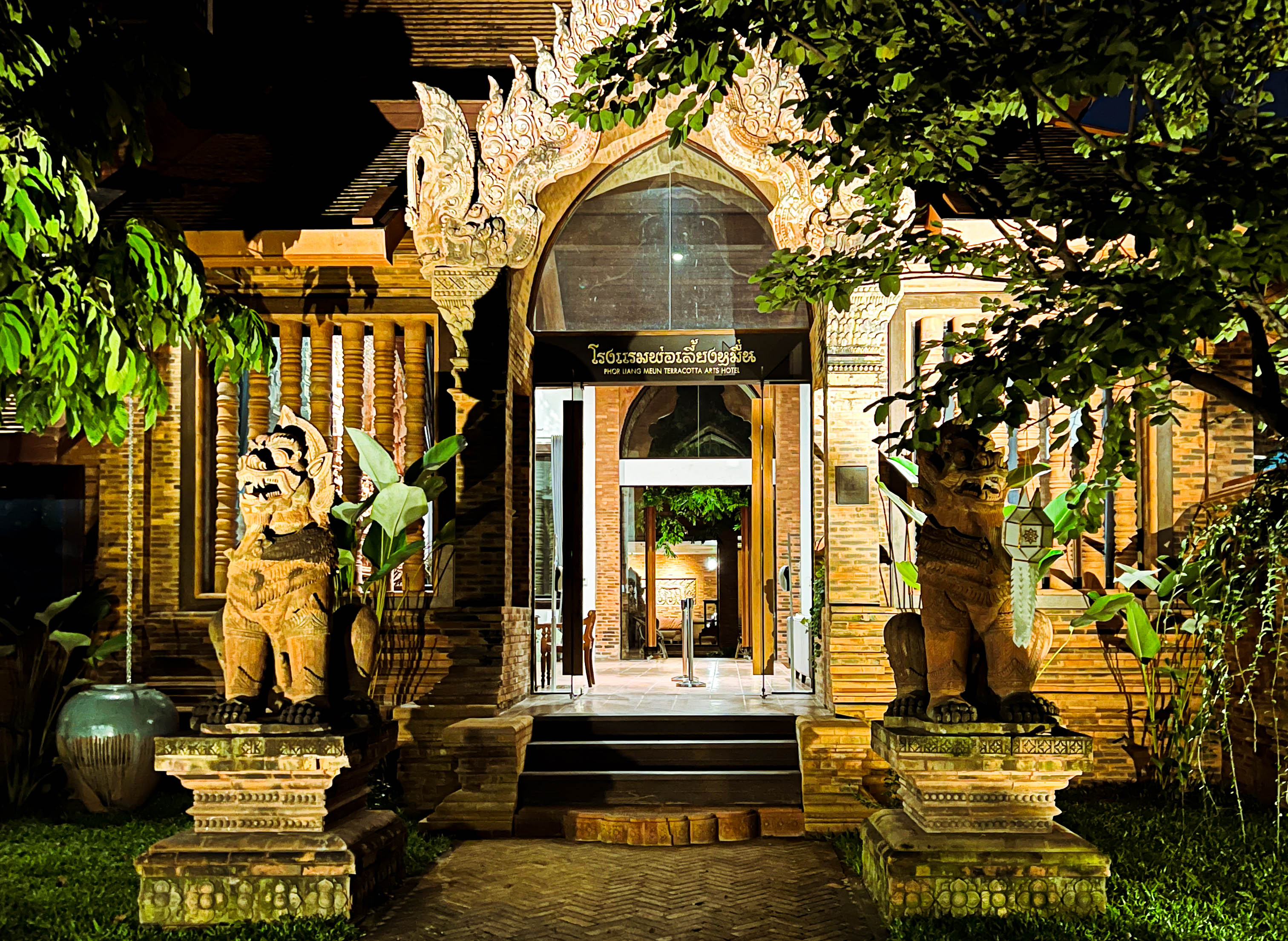 the entrance to a hotel in old town chiang mai lined with teracotta statues