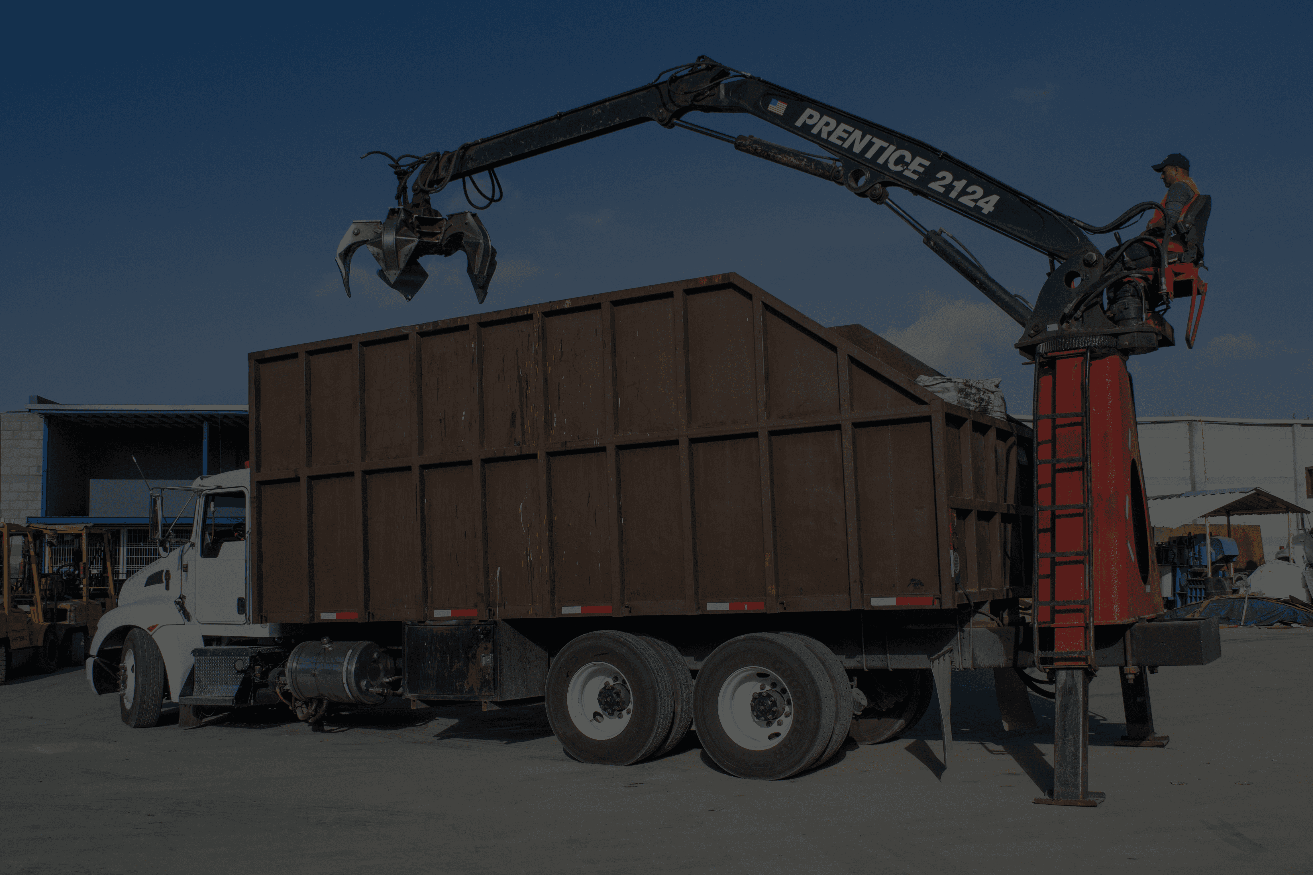 Crane truck loading debris into a large bin.