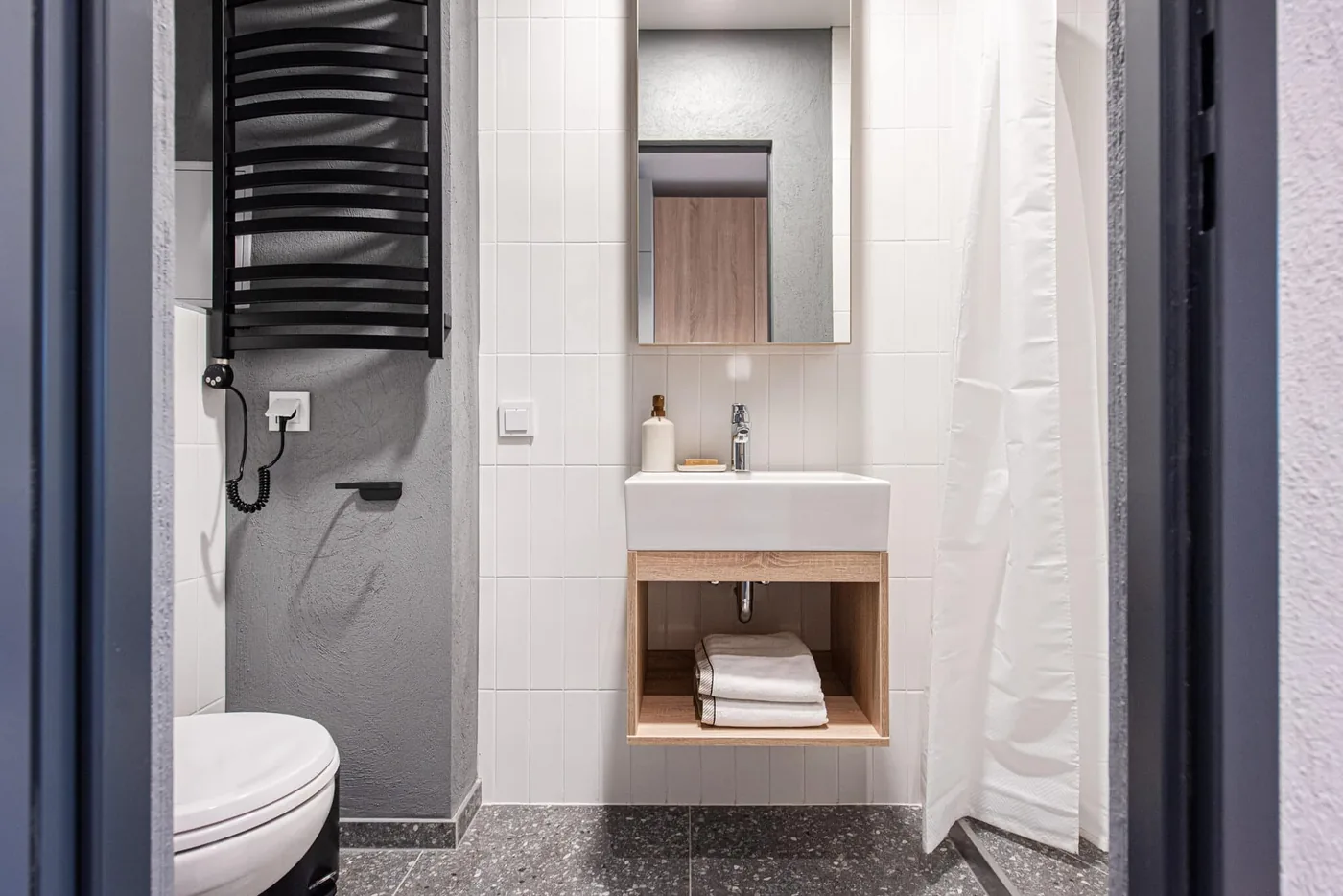 Modern private bathroom in furnished student accommodation in Vilnius with shower, sink and storage.