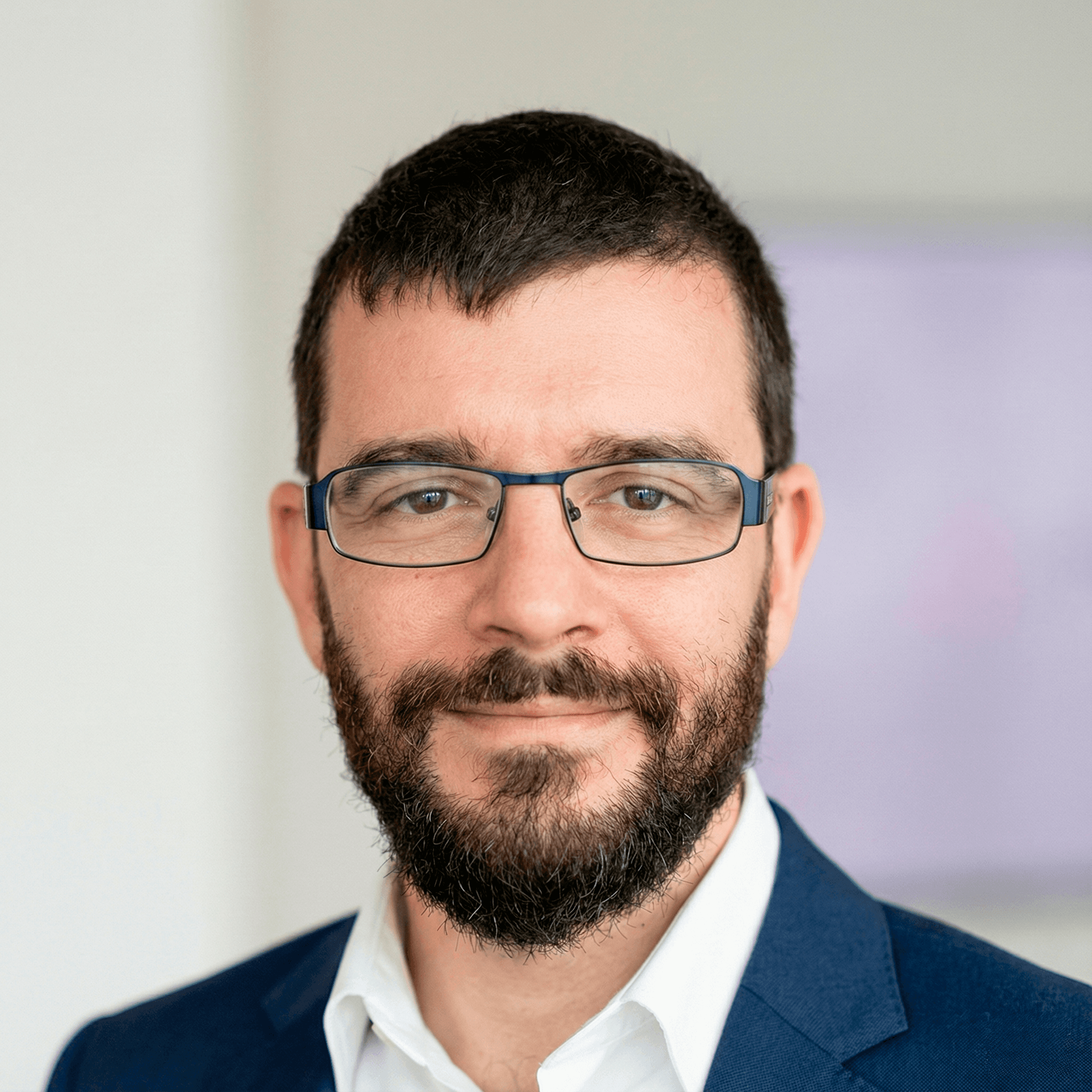 Portrait of a young man in a dark double-breasted suit and black turtleneck. Soft lighting creates a sophisticated, serious tone.