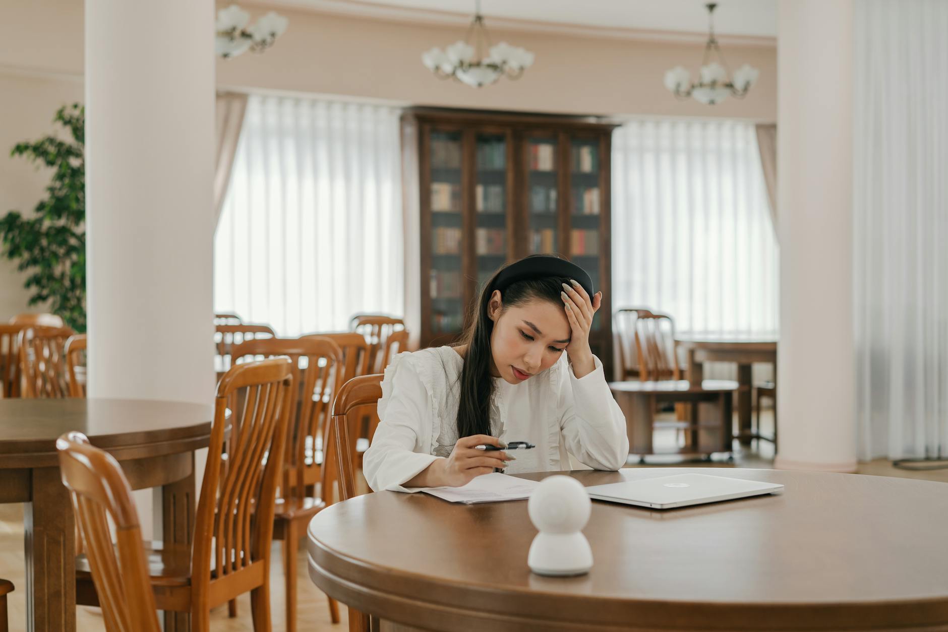 A focused teenager working alone on a laptop in a quiet, sunlit study space.
