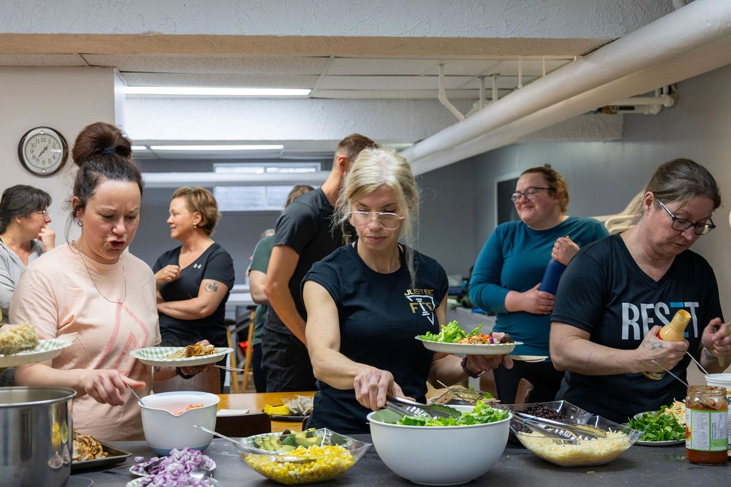 Membres de la communauté Progrès-Fit composant des assiettes équilibrées et nutritives lors d'un rassemblement axé sur le mode de vie sain.