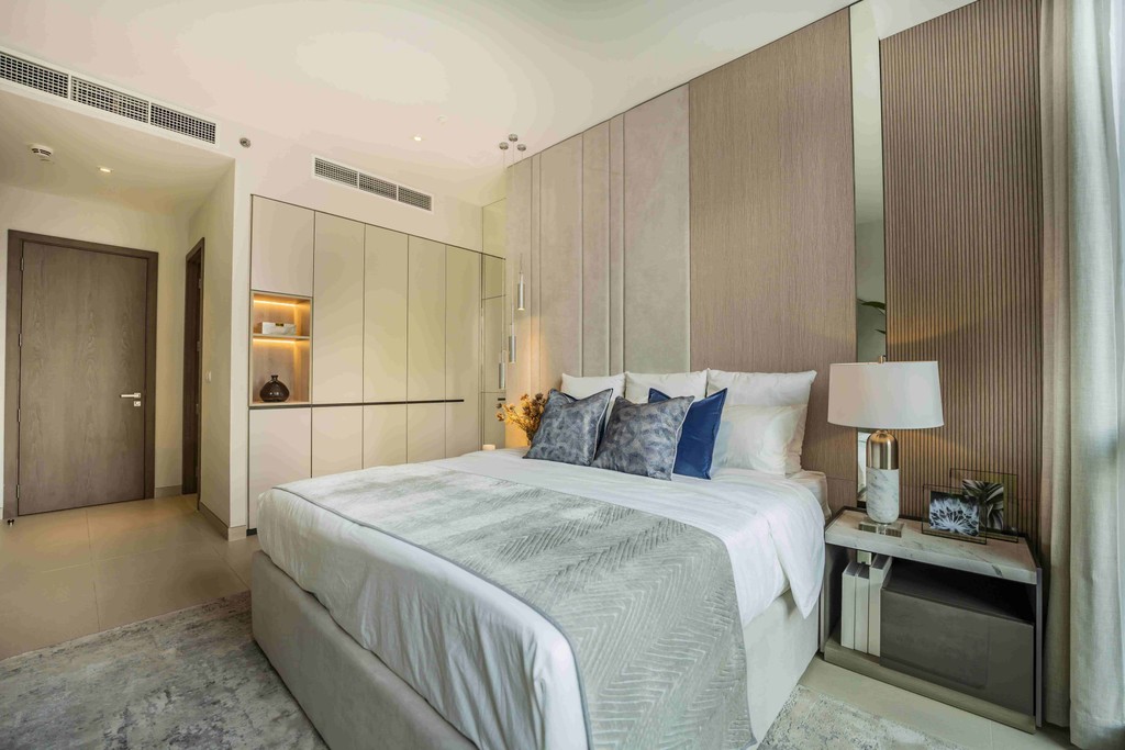 Elegant bedroom interior with a bed, dresser, and nightstand, showcasing Liv Lux's design in Dubai.