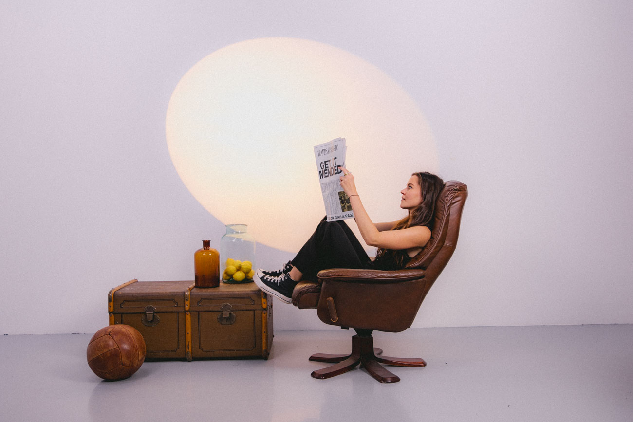 Girl sitting in leather chair reading a paper with mended logo