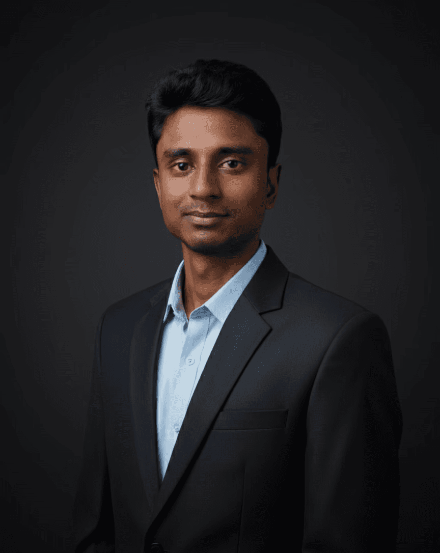 Business professional in a dark suit and light blue shirt posing against a dark background