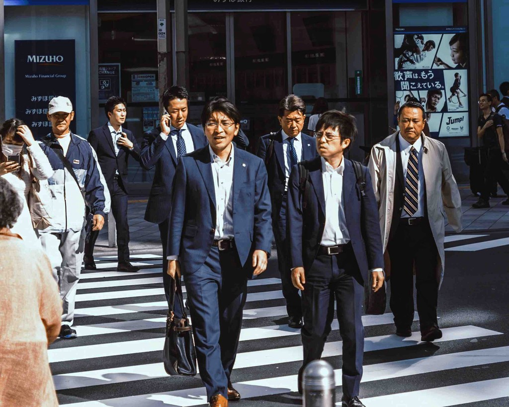 Japanese business men walking across the street in Tokyo side by side.