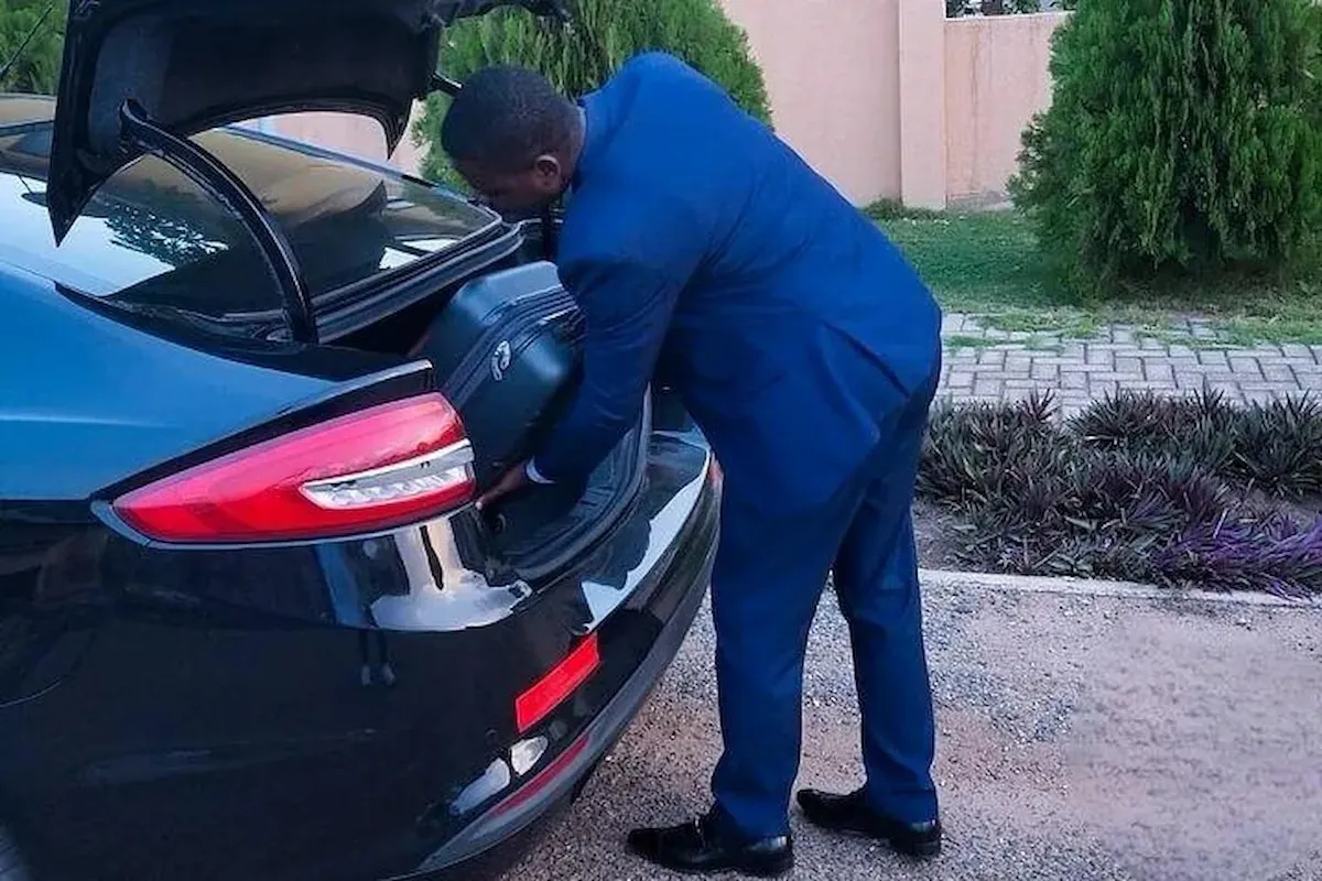 Chauffeur loading luggage into a private transfer vehicle.
