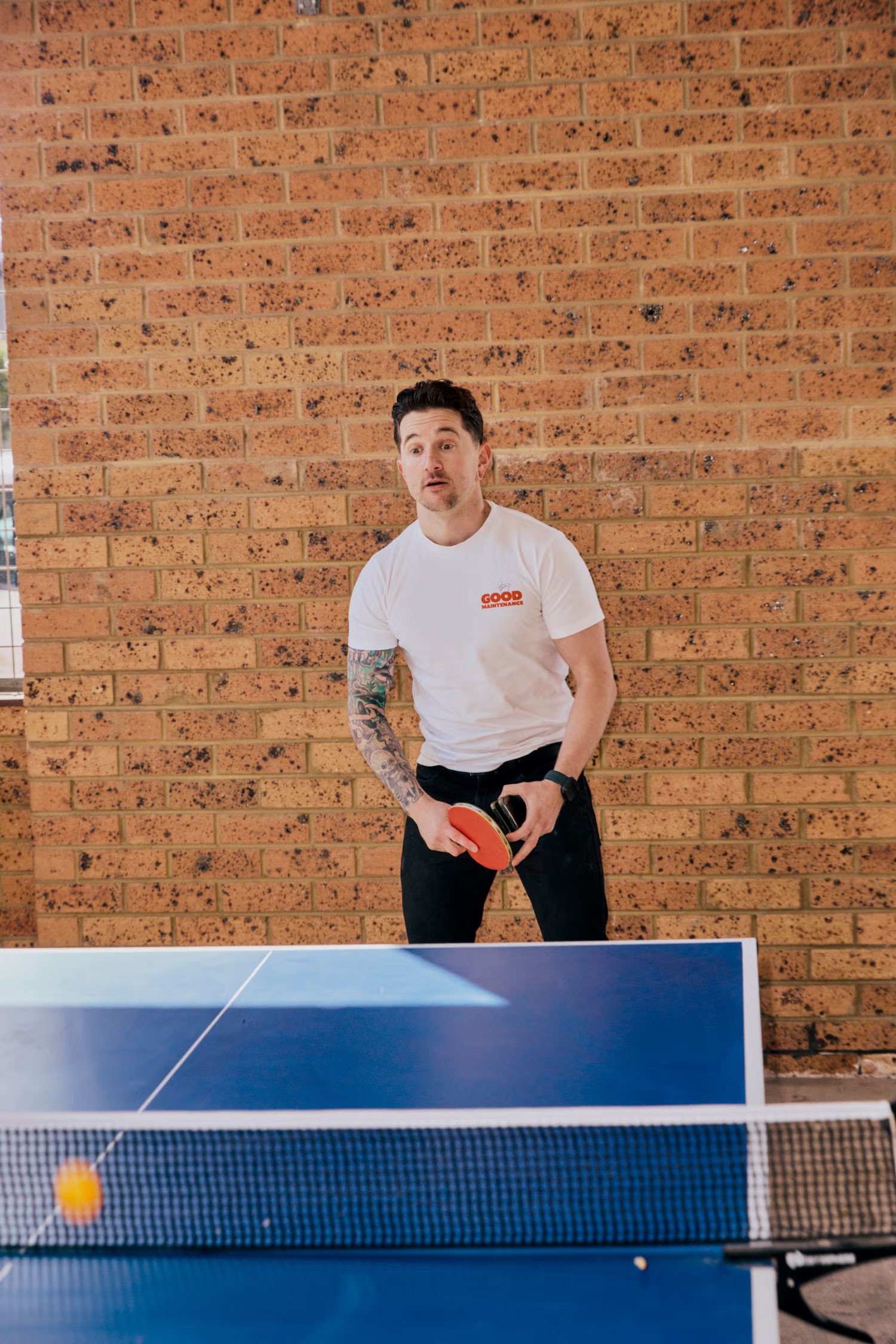 Team Member in Good Maintenance shirt playing table tennis