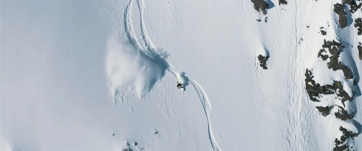 Guy snowboarding and leaving a big spray