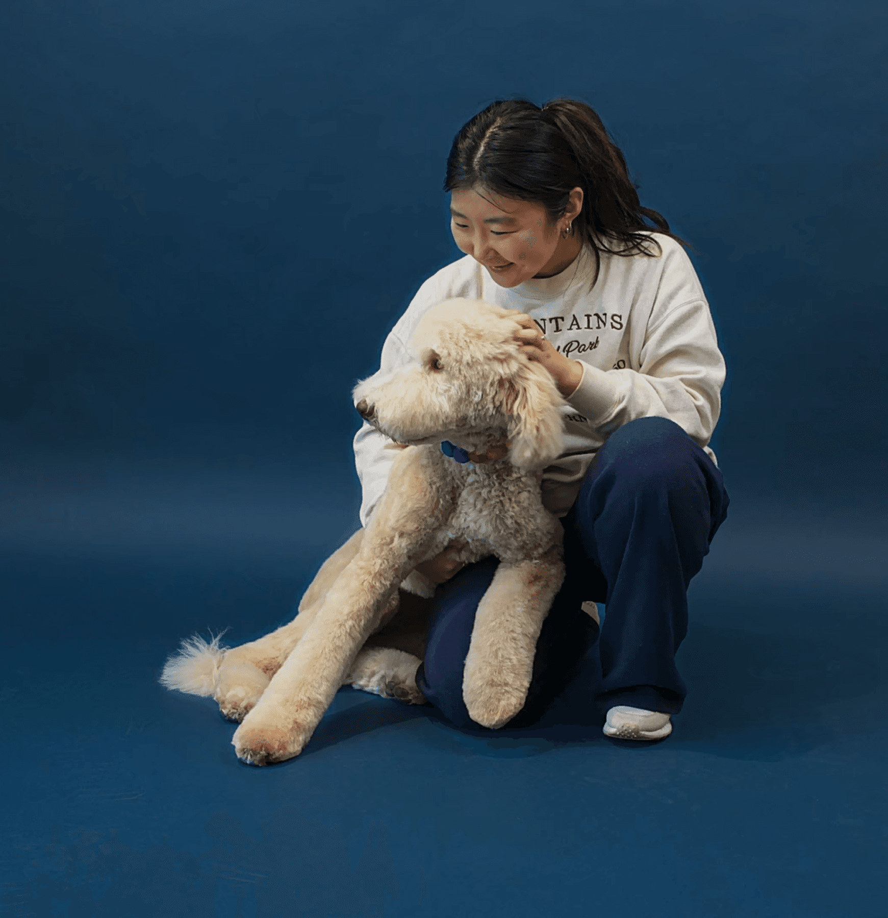 Candid photo of a young woman holding a fluffy puppy and laughing to reflect connection, playfulness, and premium pet care.