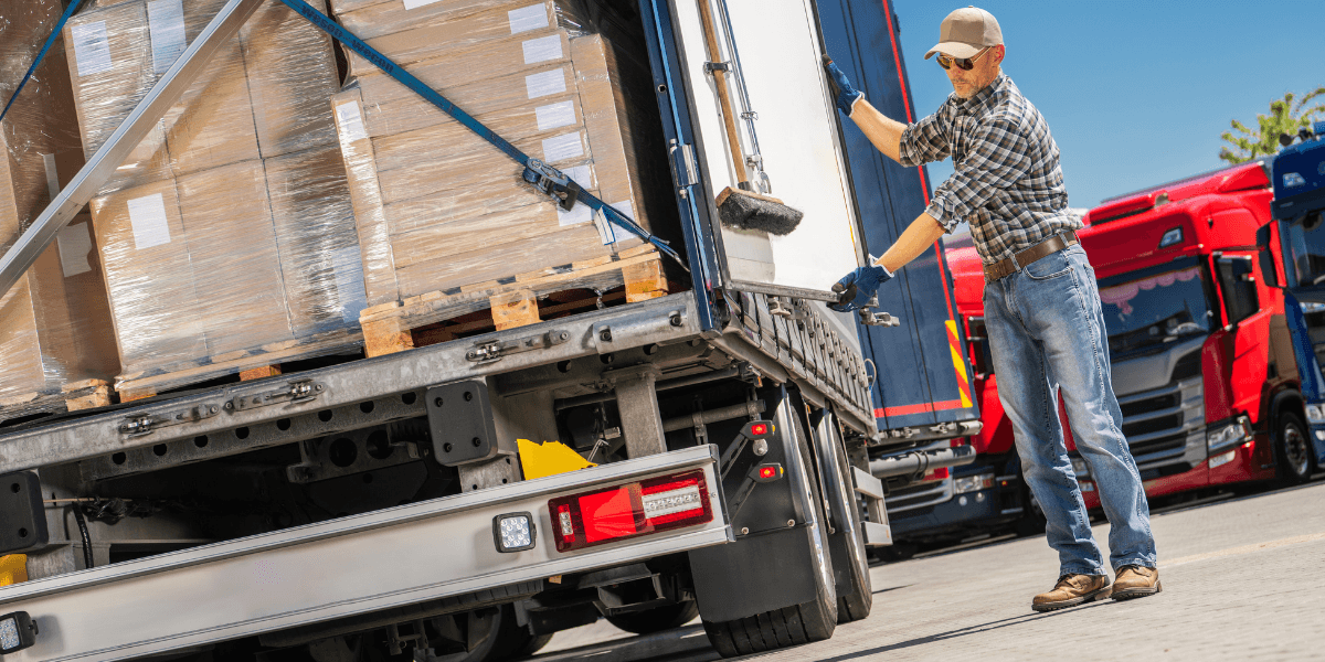 Logistics worker securing the doors of a truck loaded with custom export crates.