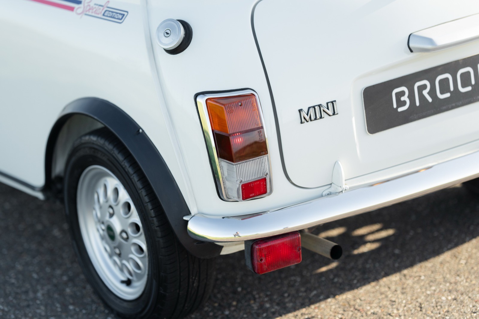 Close-up of the rear of a vintage white car, showcasing the tail light and part of the bumper.