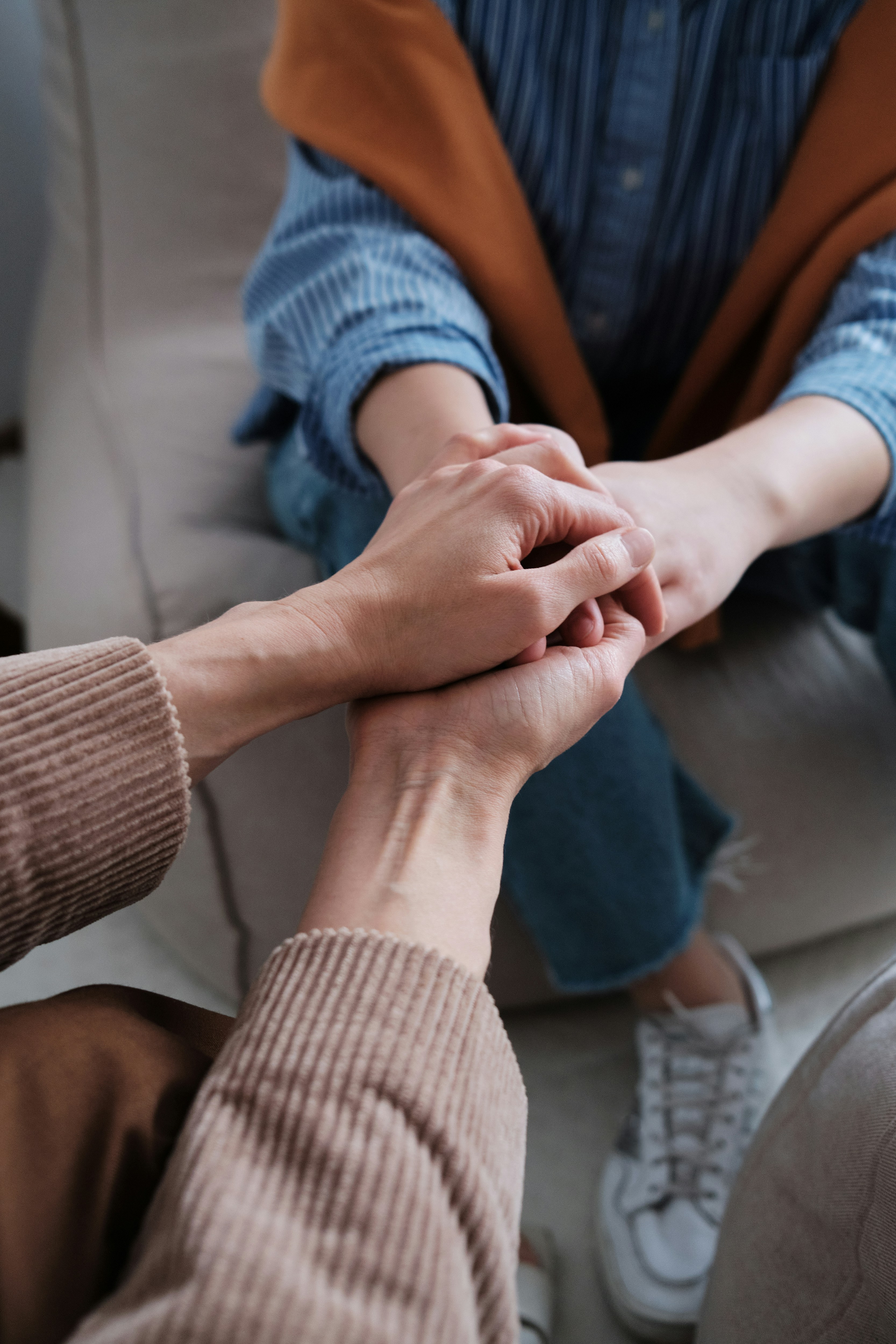 Supportive hand-holding between two individuals, representing psychological care and solidarity amidst wartime trauma in Ukraine.