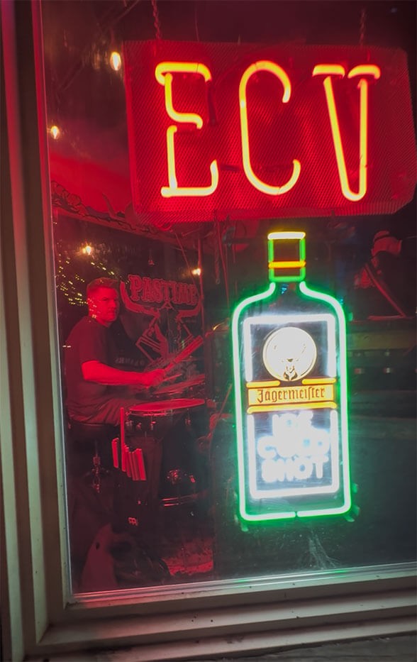 Holland Barry on drums as seen through the neon lights outside The Pastime Club in Truckee.