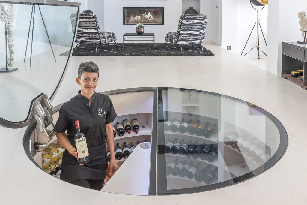 Service staff presenting private dining and wine service within luxury villa interior environment.