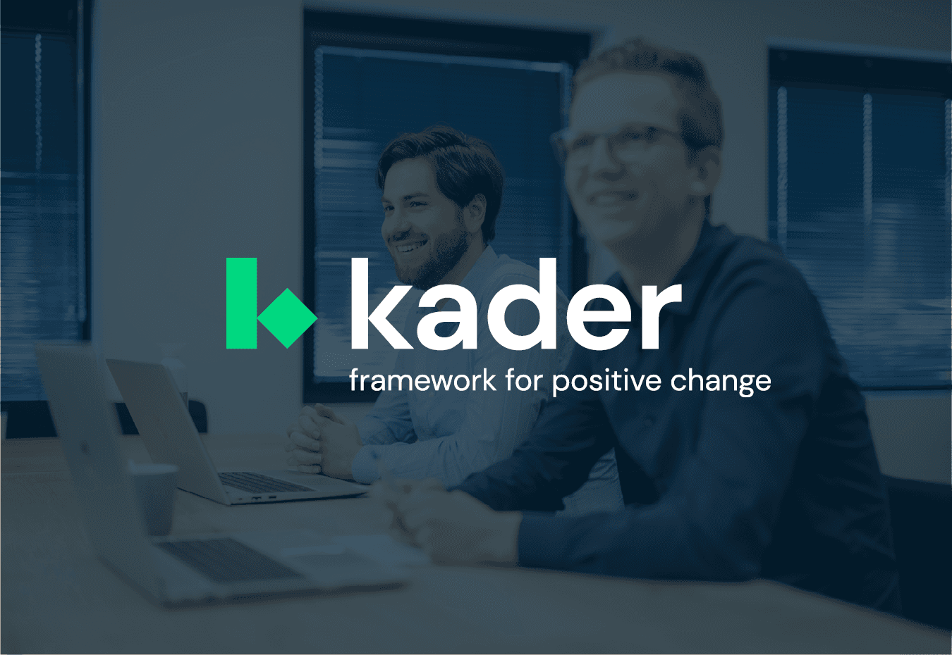 Drie medewerkers van Kader in een magazijn, waarbij één medewerker een presentatie geeft en de anderen aandachtig luisteren, met documenten in de hand.