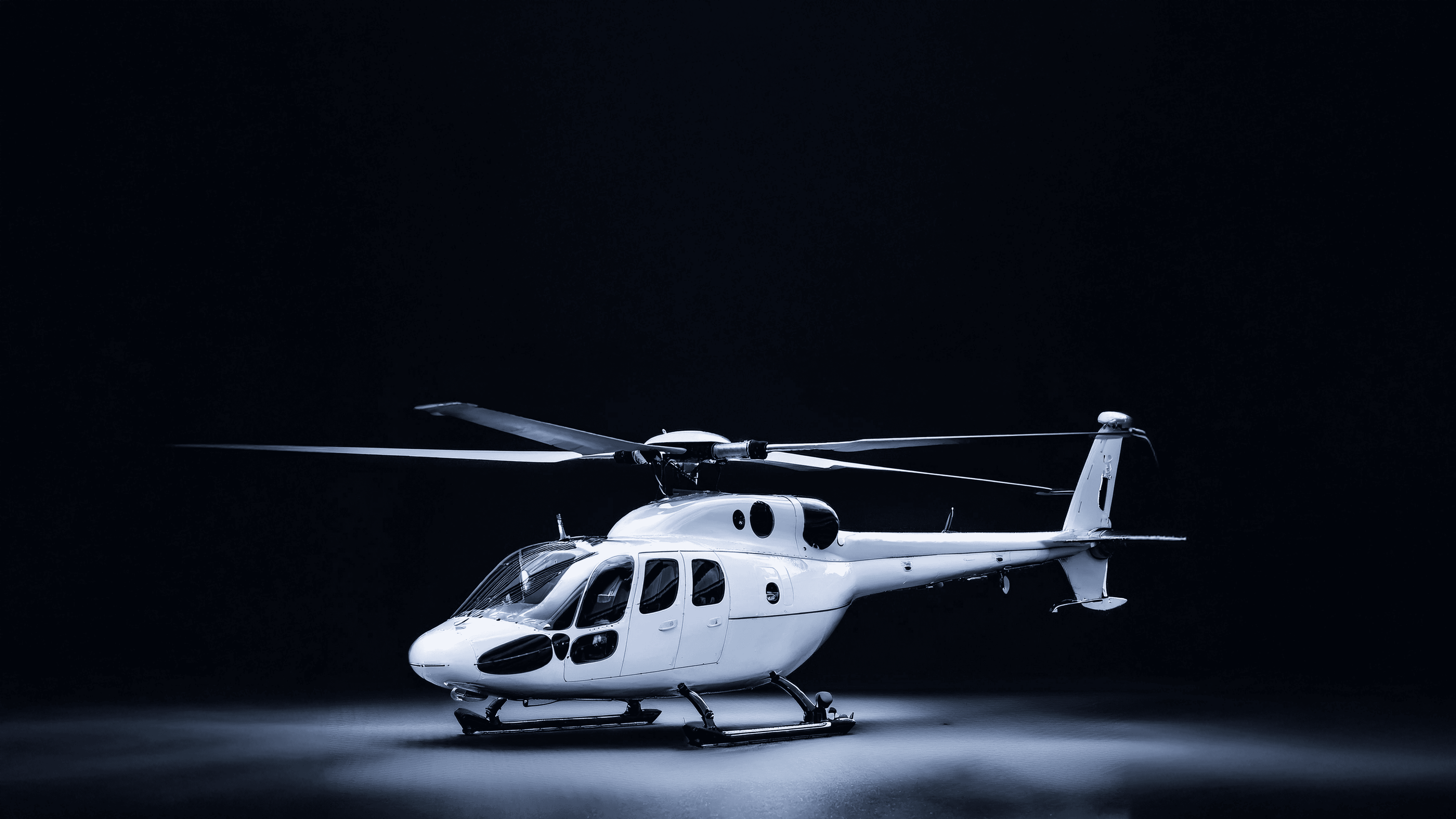 Hubschrauber in dunkler Umgebung, Rotorblätter und Cockpit sind sichtbar, wodurch das Design und die Funktionen des Fluggeräts verdeutlicht werden.