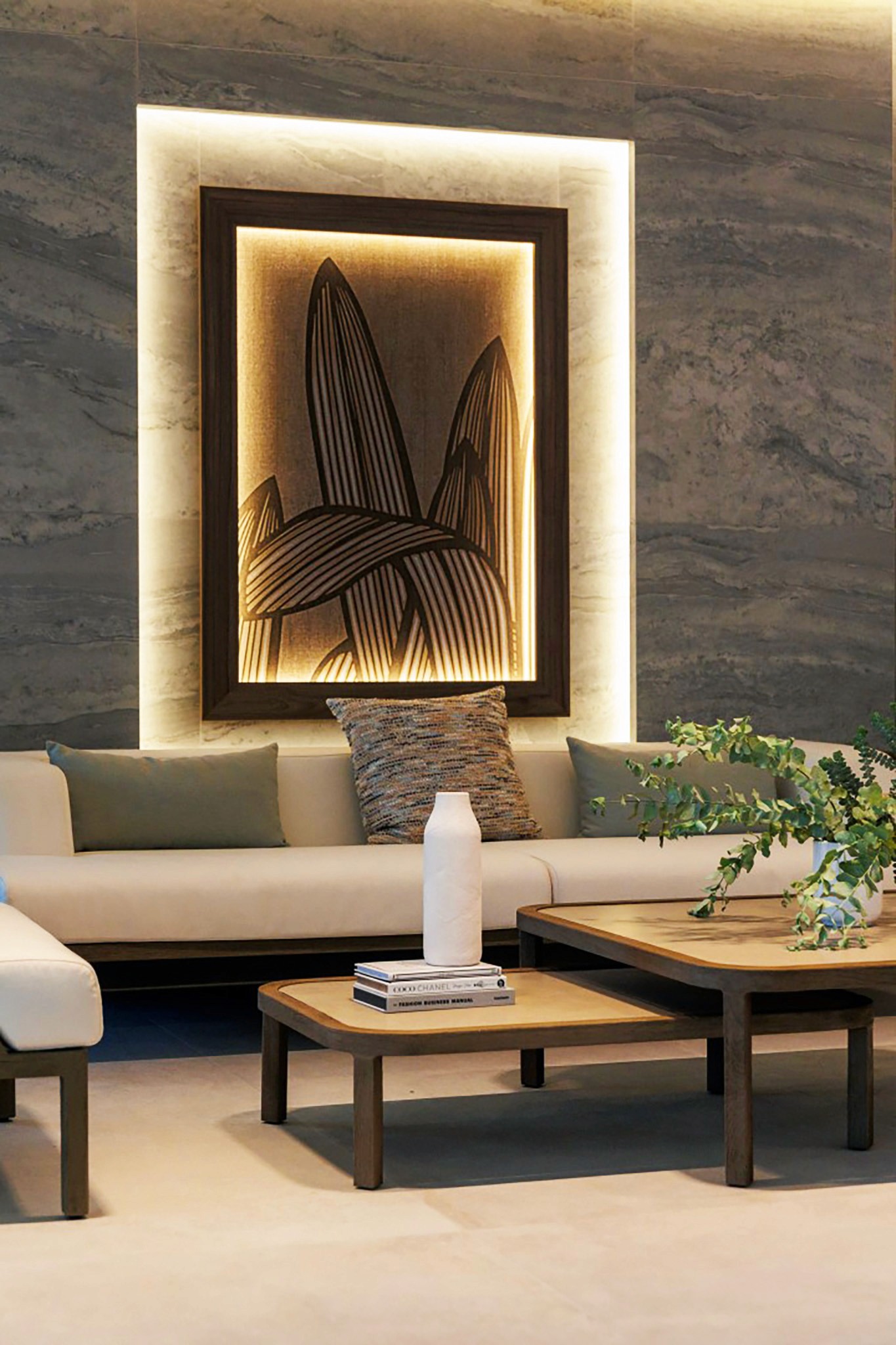 Villa Trio lounge detail with backlit framed artwork, neutral sofa, and layered coffee tables