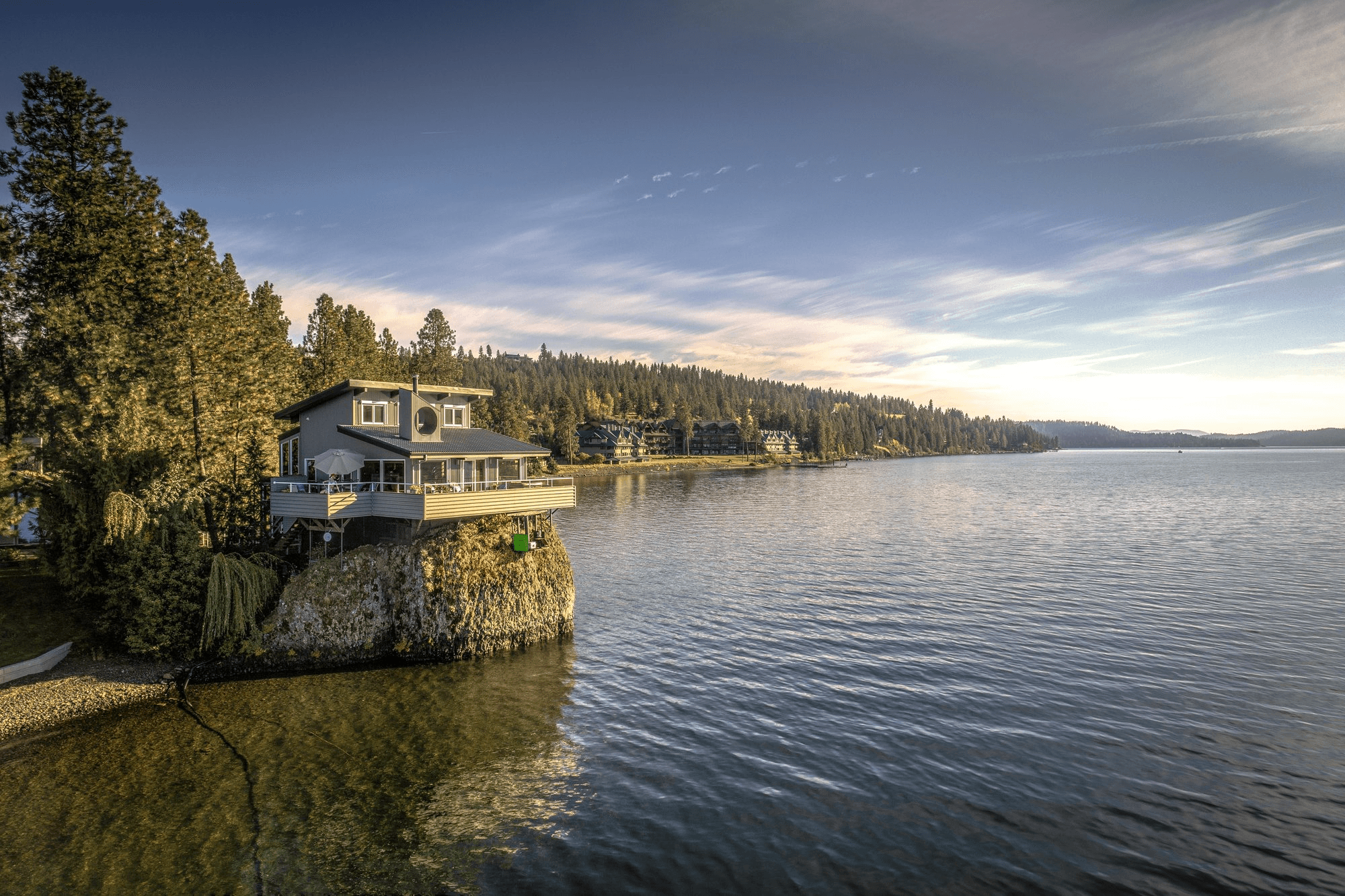 Modern lake house on cliff by forest shoreline