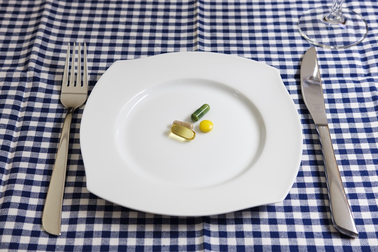 Assiette avec des pilules sur nappe à carreaux bleus, diététique et compléments alimentaires.