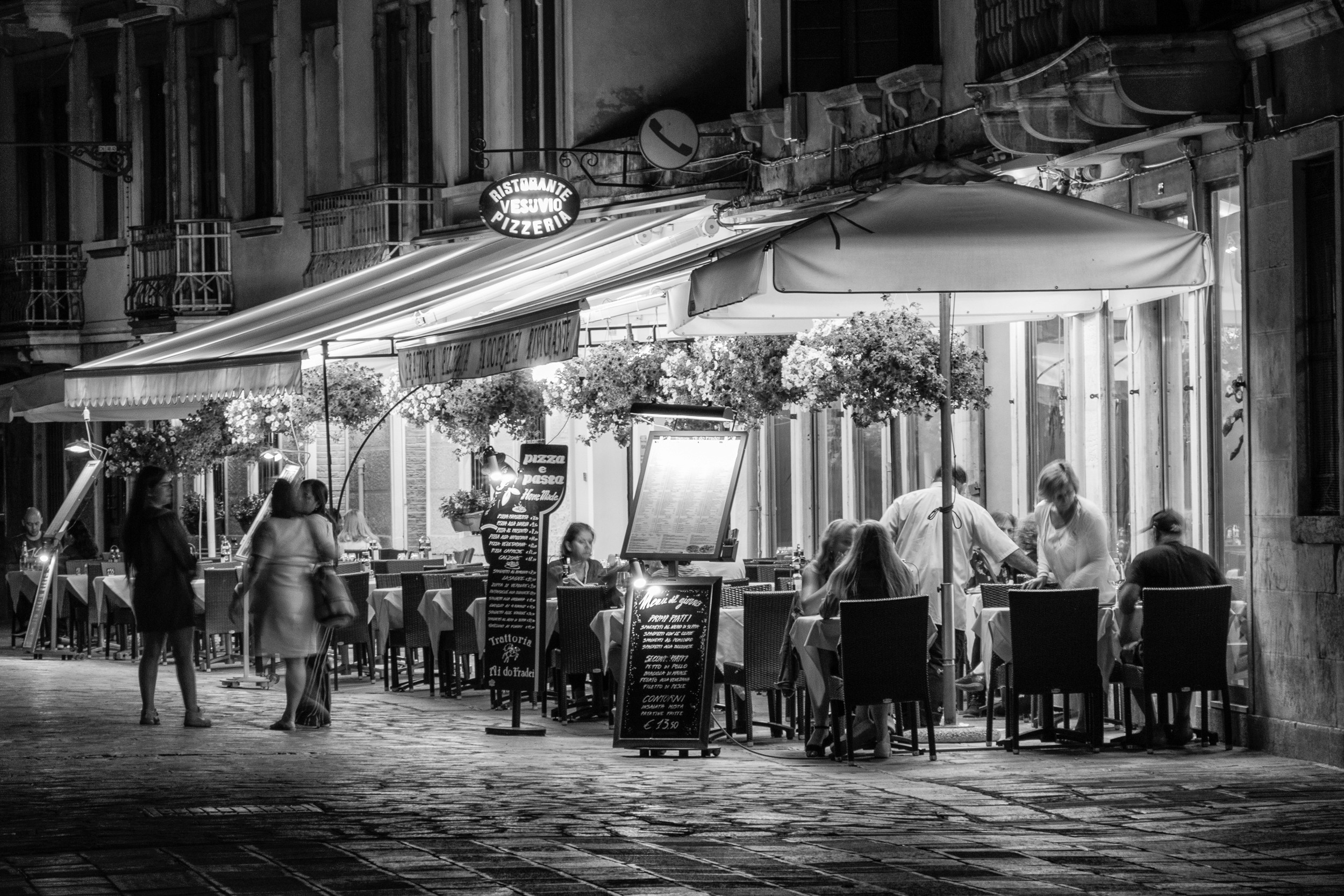 Outdoor café with diners illuminated by warm lights in a European street scene at night