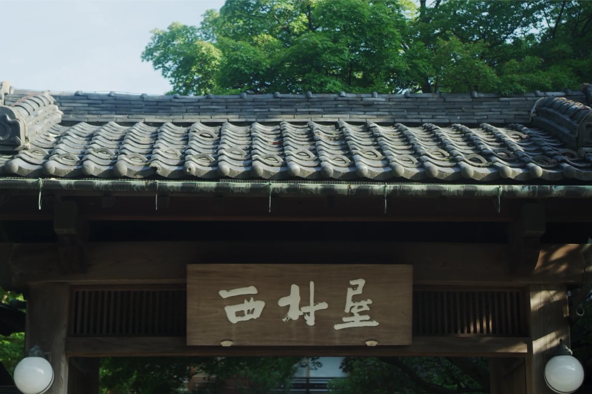 The carved name board and timber gate of Nishimuraya Honkan, a long-established Kinosaki inn.