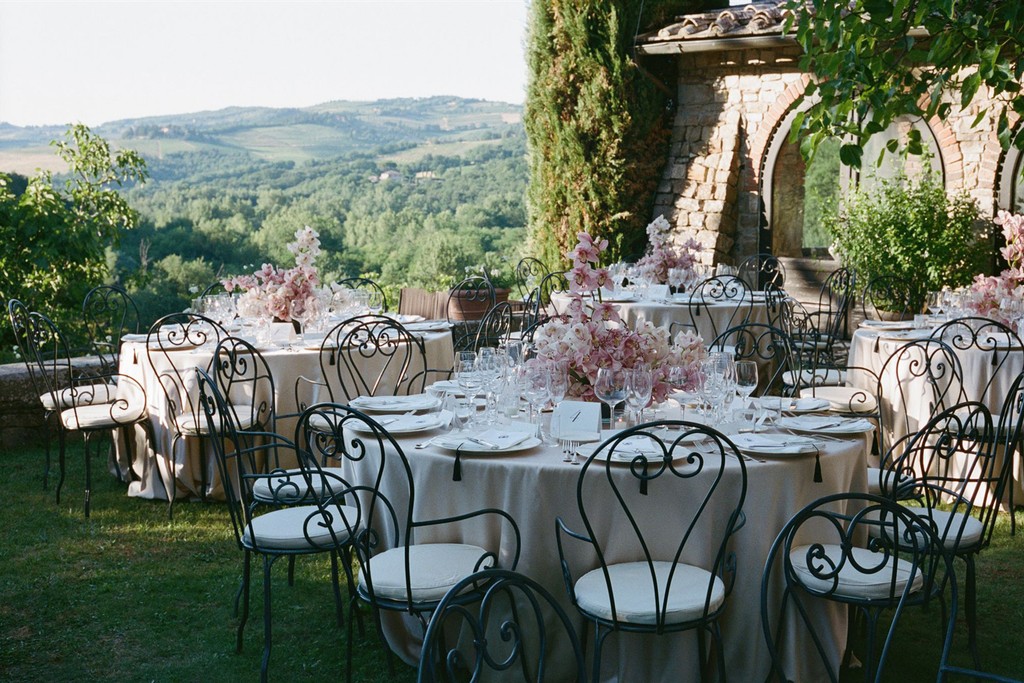 Outdoor wedding reception tables set in a garden overlooking rolling hills