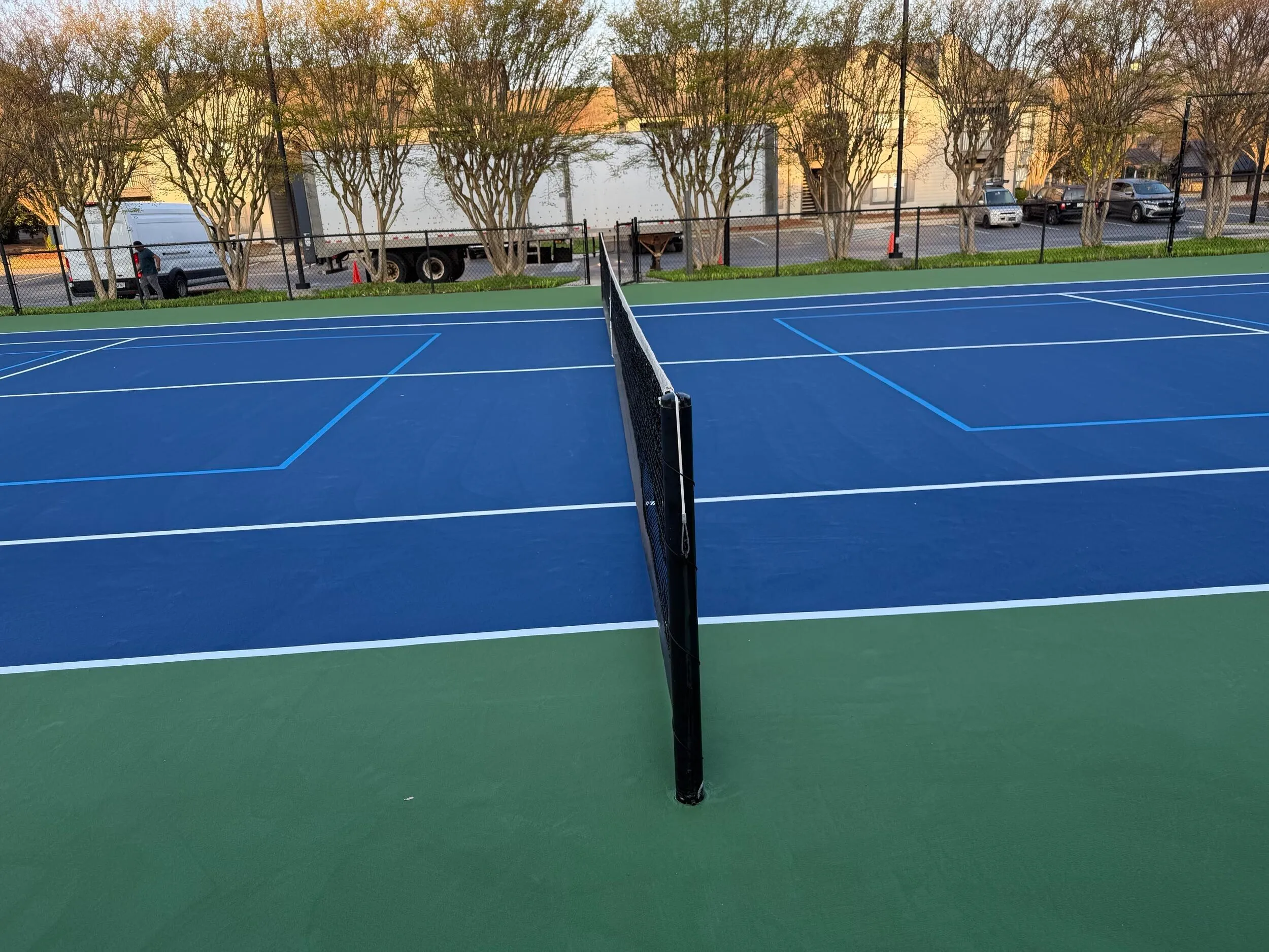 Resurfaced tennis court net and blue playing surface at Weston Ranch apartments in Madison, AL
