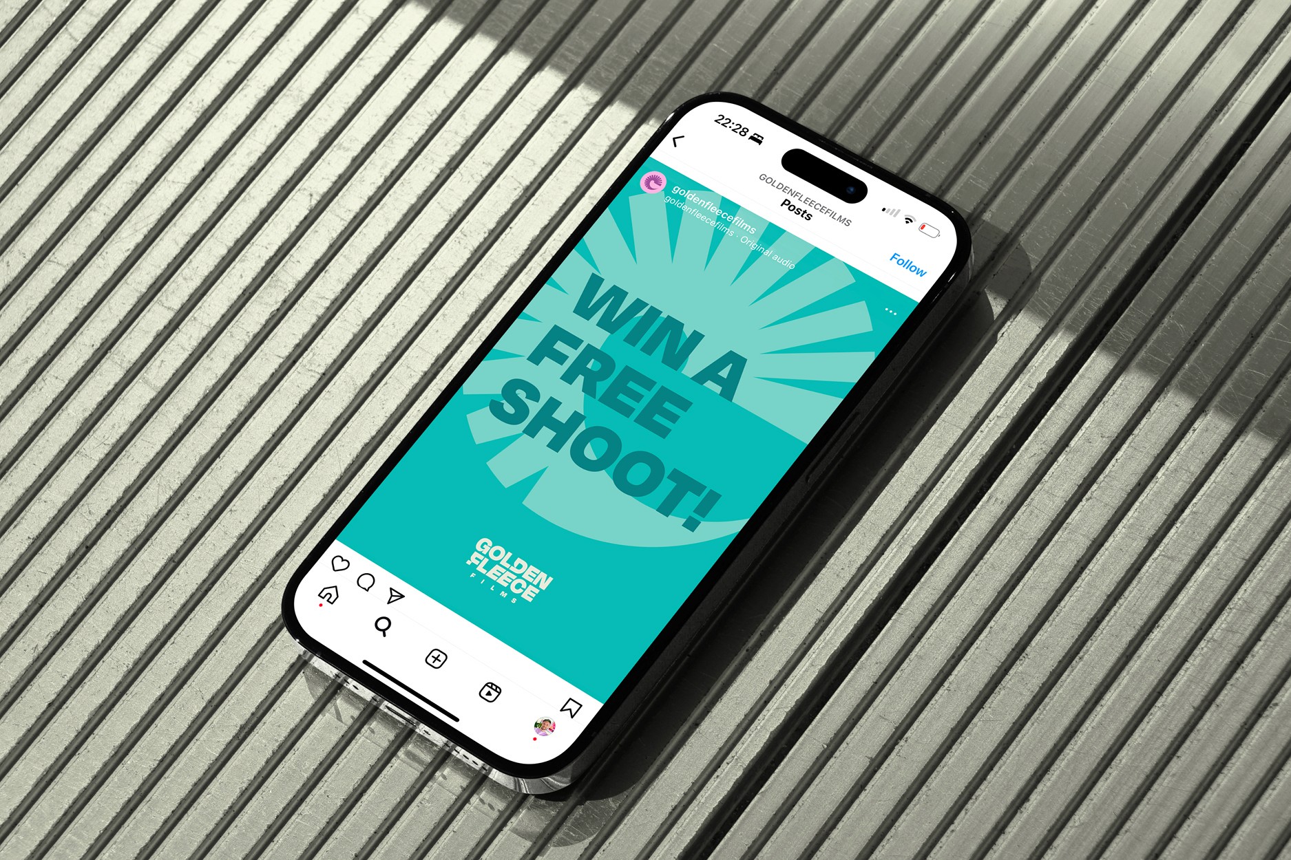 Phone displaying a Golden Fleece Films Instagram post with teal background and bold text reading ‘Win a Free Shoot!’.