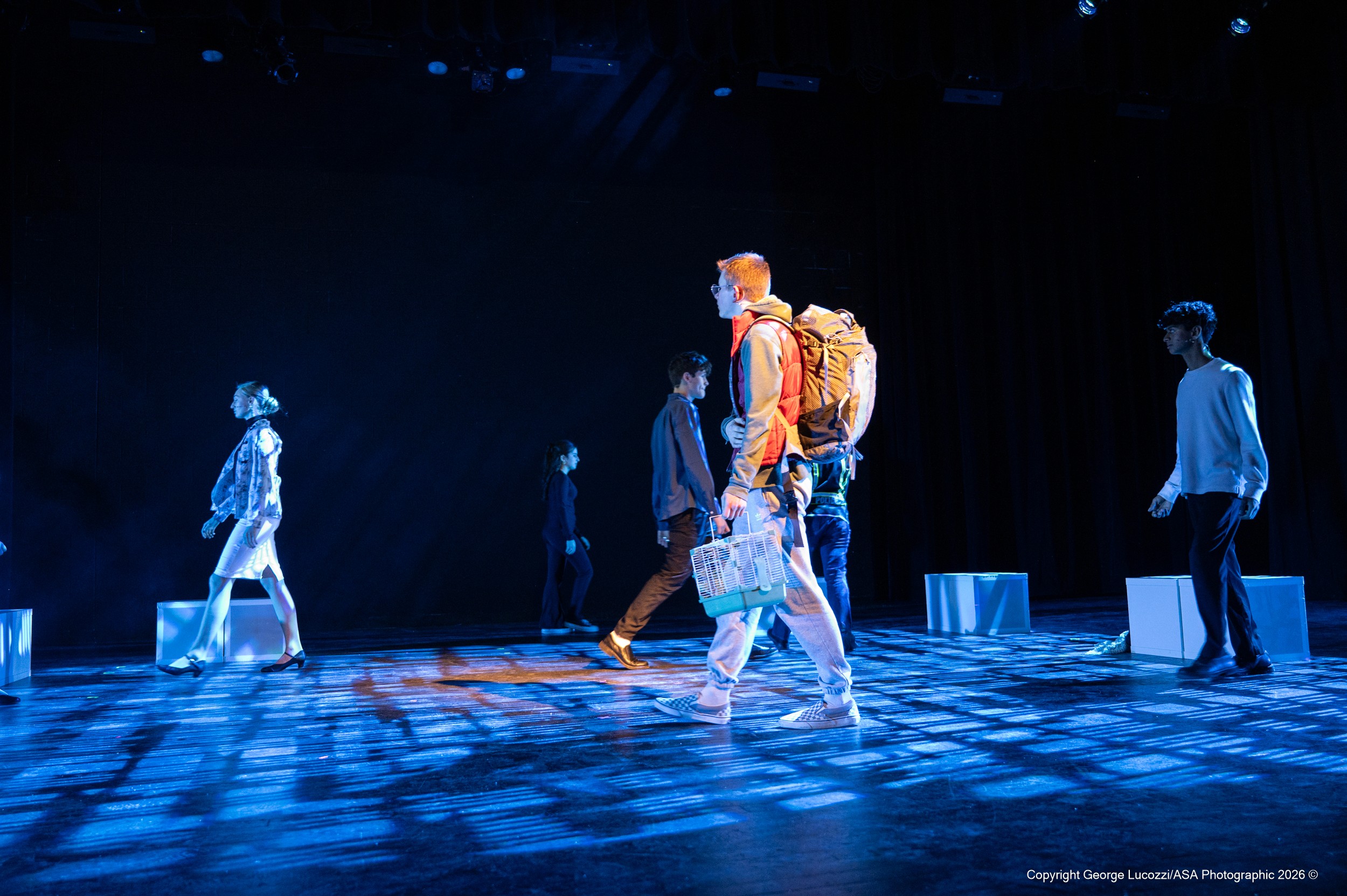 The “Voices” traverse the stage beneath crisp blue overhead beams with Rosco Squares (77524) gobos, while Christopher moves among them in a contrasting warm followspot that isolates him from the patterned environment.