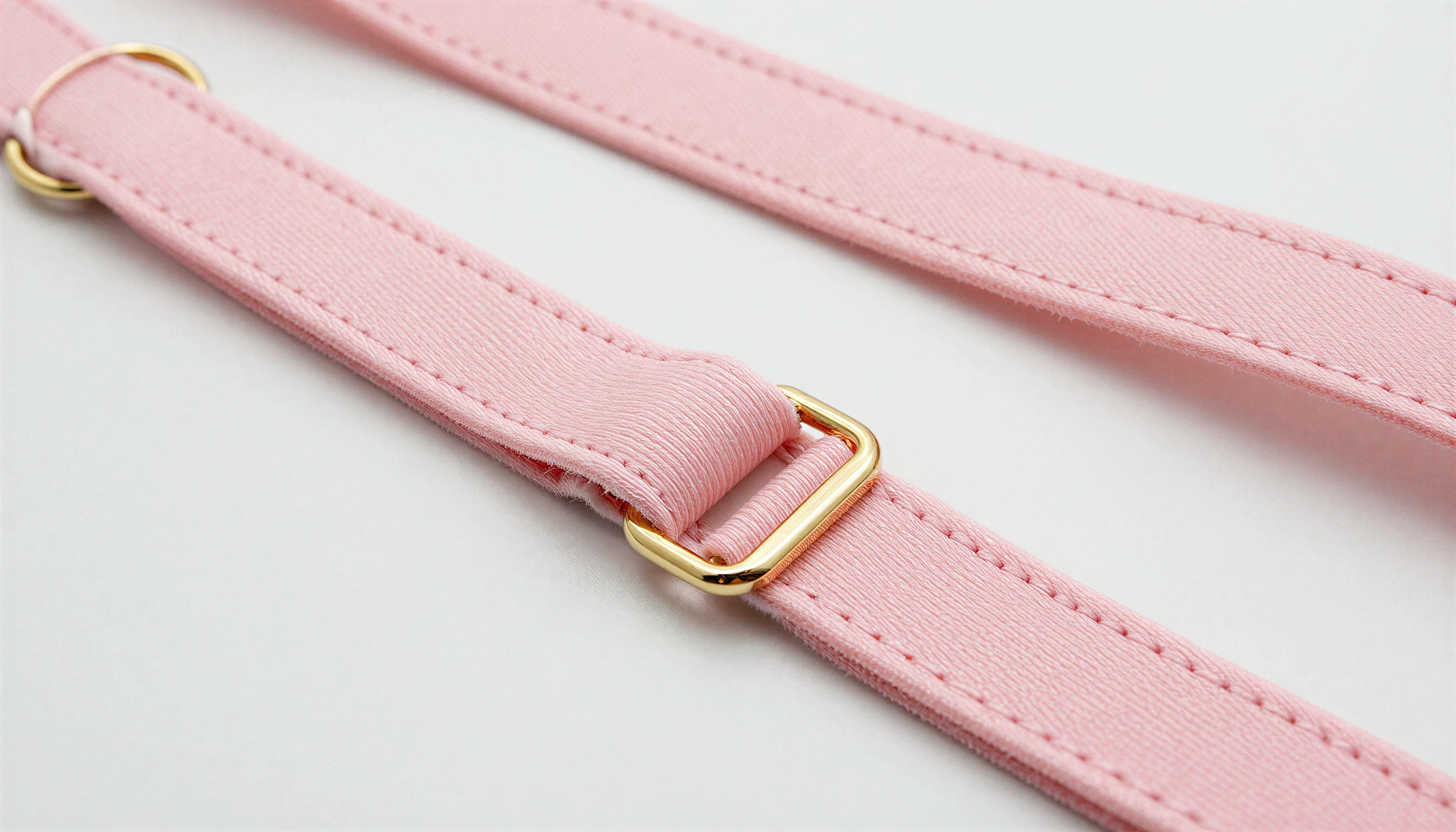 Pink lingerie strap with gold hardware in close-up.