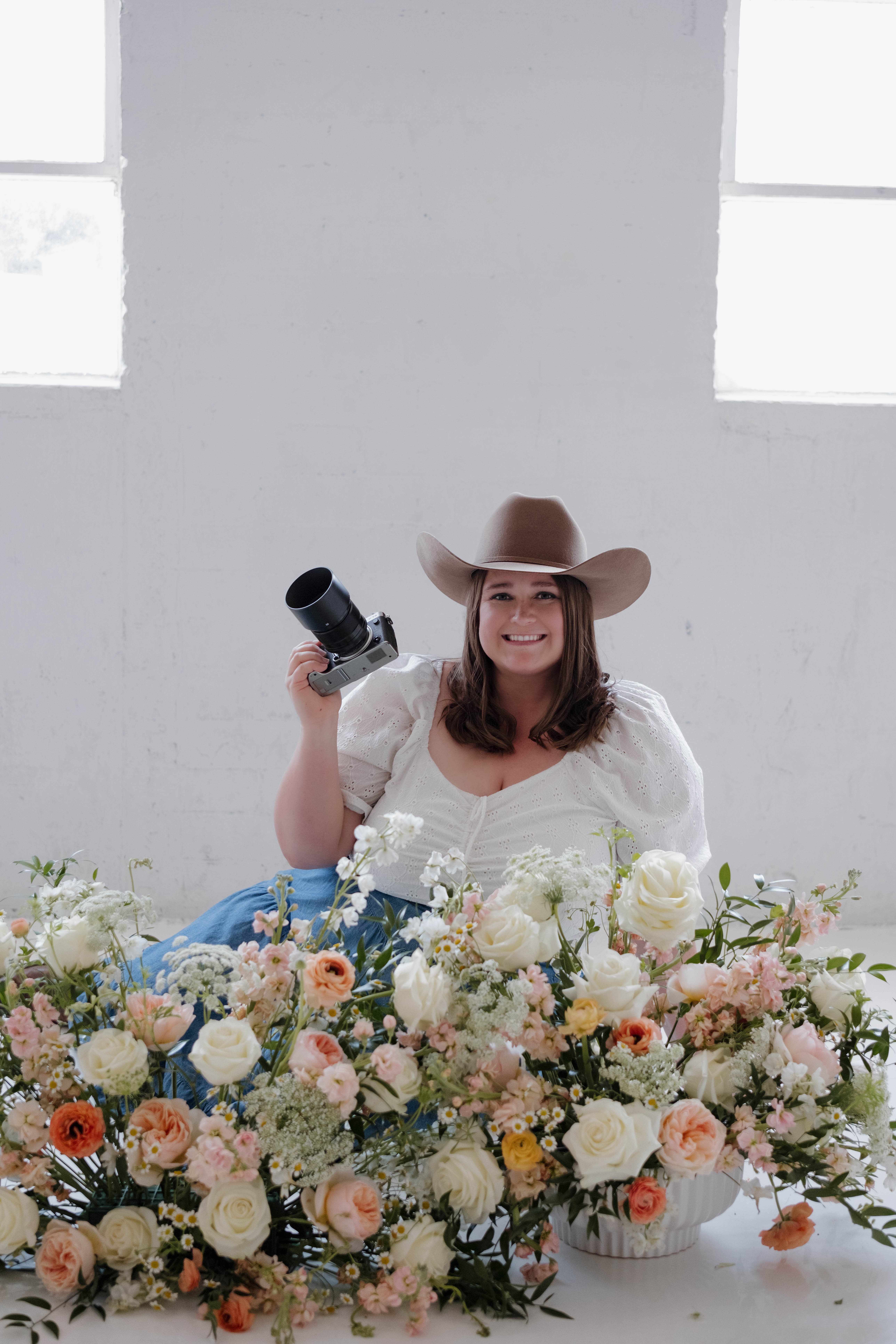 Candid couples portrait in Chandler, Arizona, featuring a man with dreadlocks and a woman in a white dress embracing under a leafy canopy.