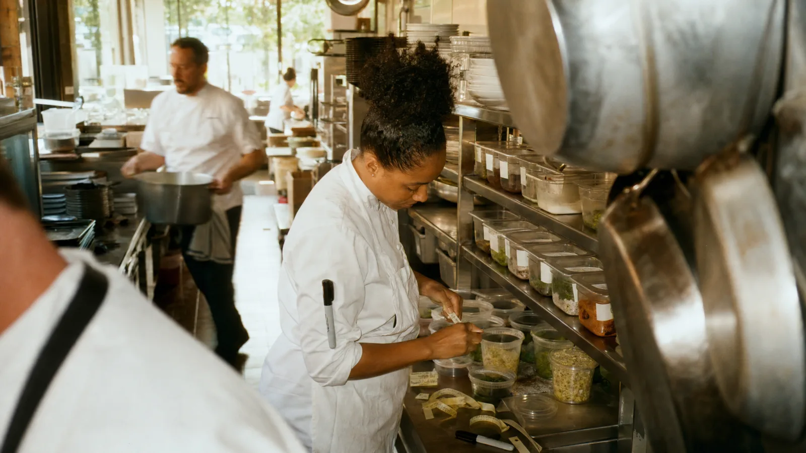 Sous chef rietichetta con il pennarello i contenitori delle preparazioni sullo scaffale d'acciaio