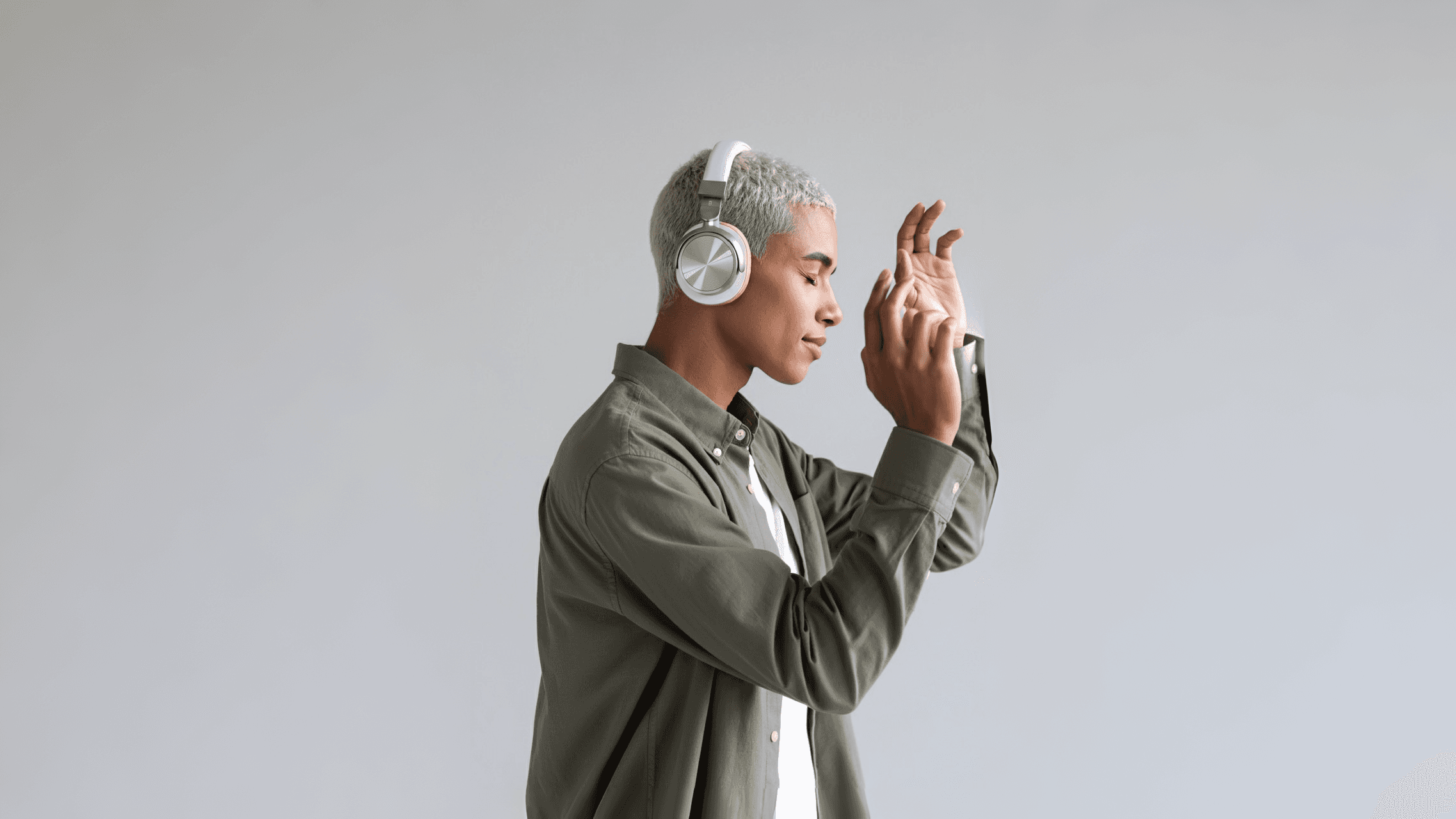 Man wearing silver headphones listening to music and dancing.