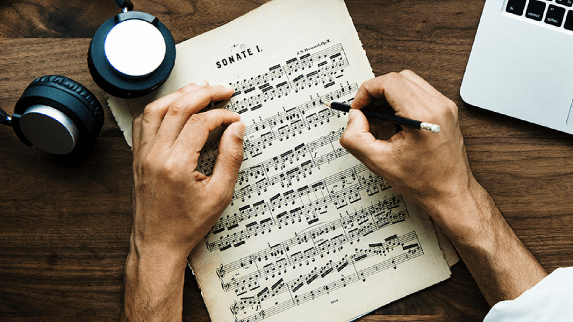 A high angle shot of a person's hands holding a pencil over music sheets
