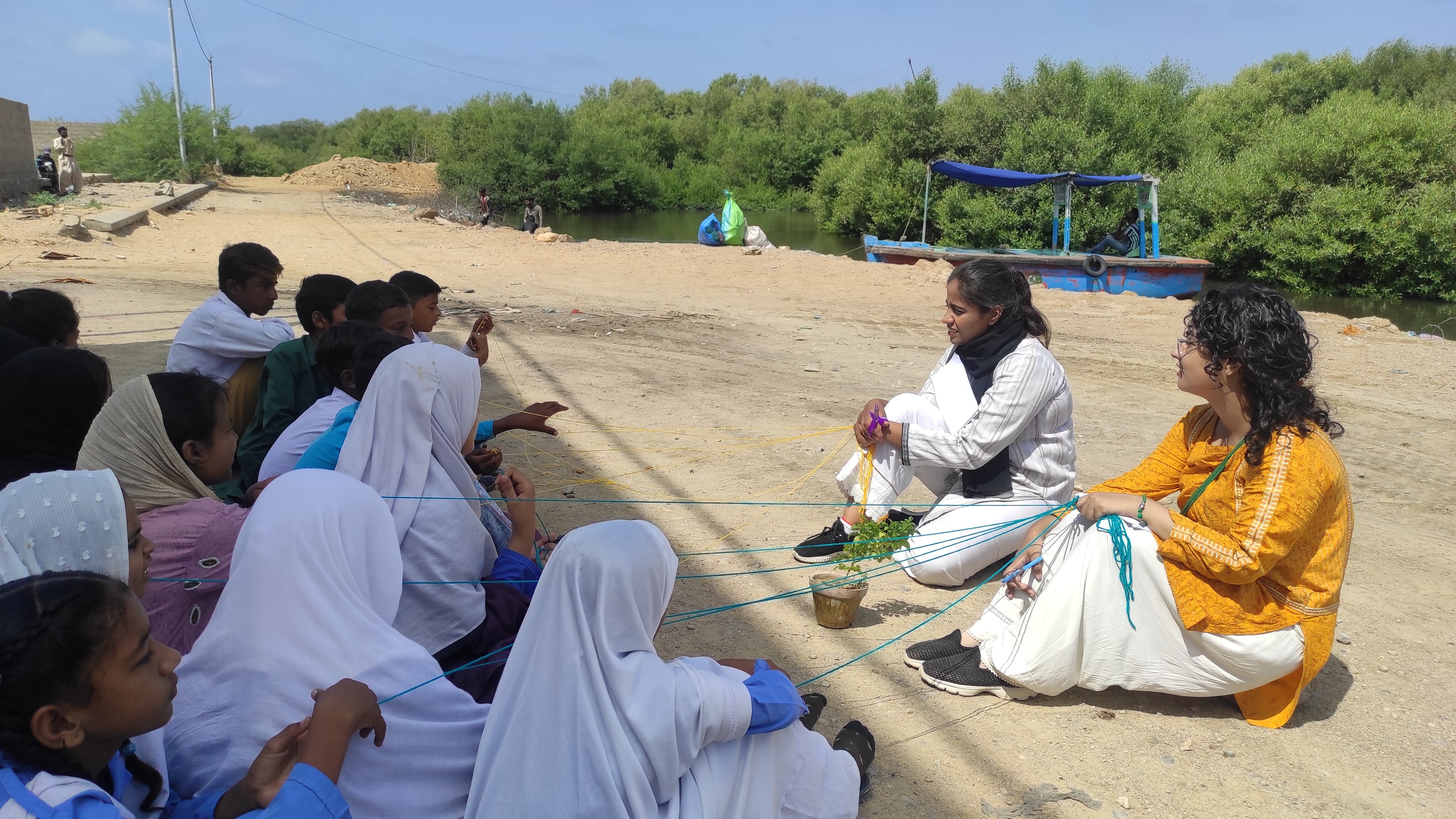 Two facilitators from CFAW teaching young children about turning trash into treasure, while ideating on poetry. They are in an outdoor setting.