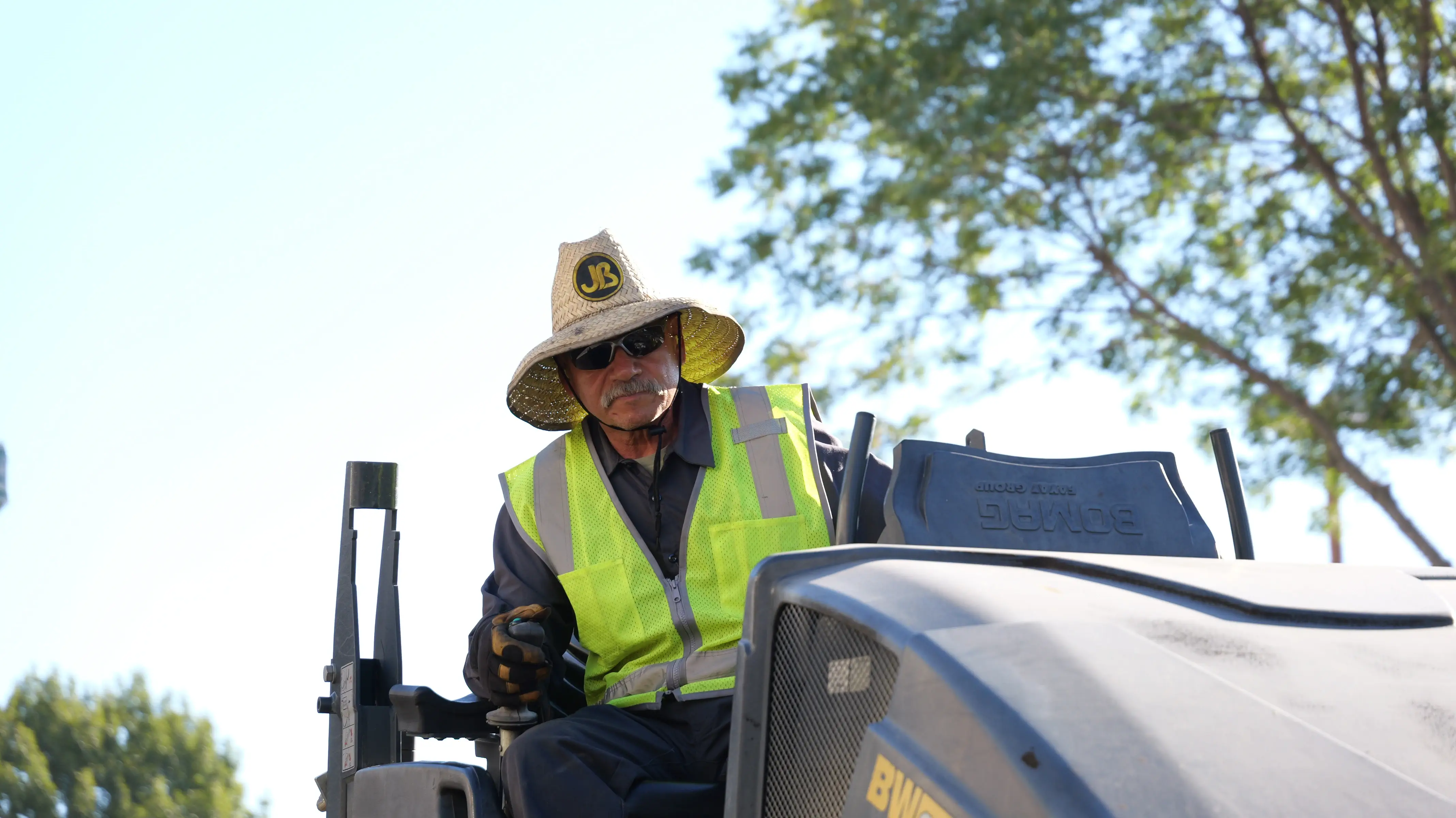 Roller machine operator compacting new asphalt pavement