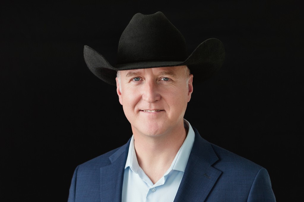 Professional executive portrait of a man wearing a cowboy hat against a dark background, projecting confidence, leadership, and Texas-based personal branding.