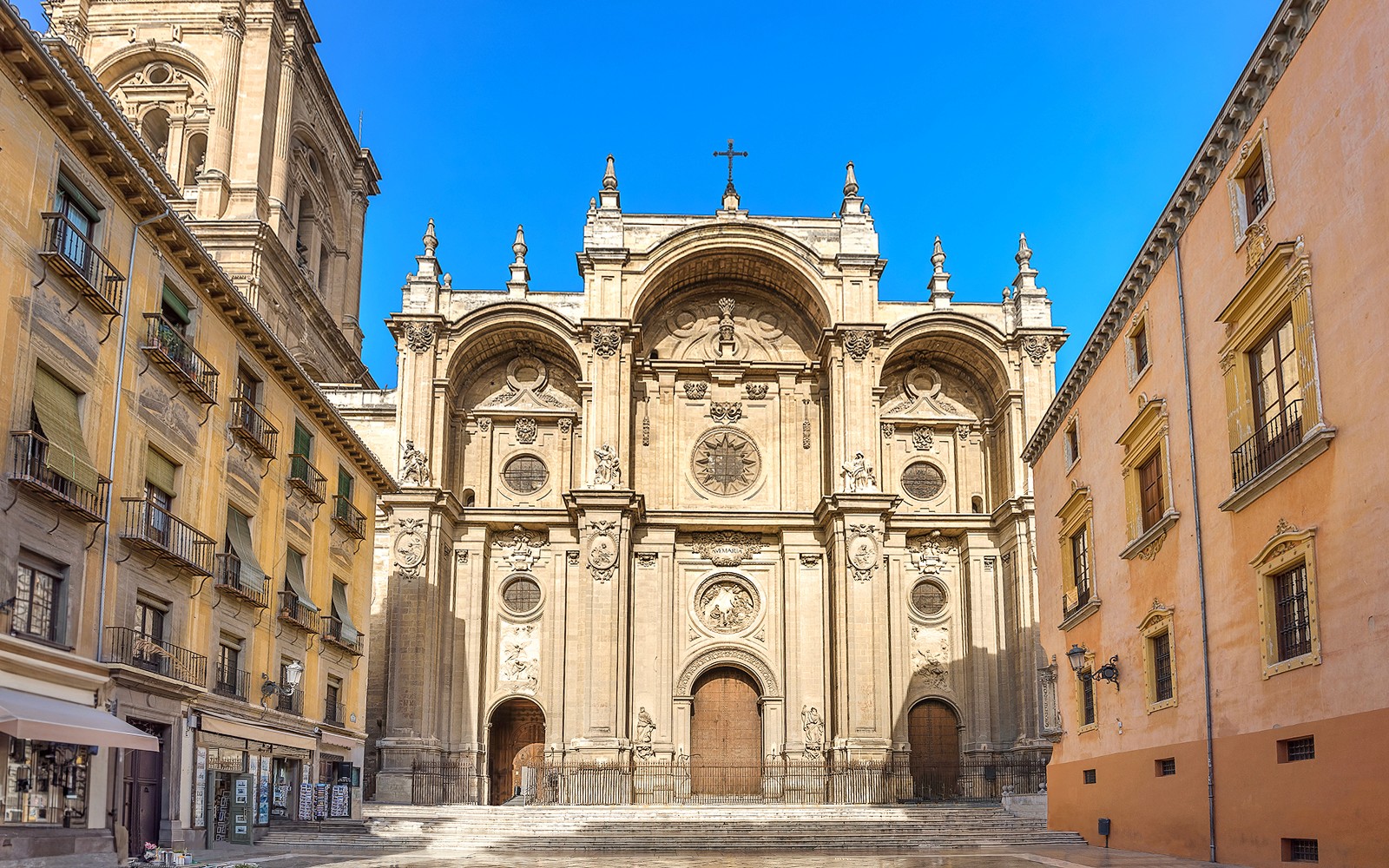 Granada Cathedral entrance with ornate facade and surrounding historic buildings.