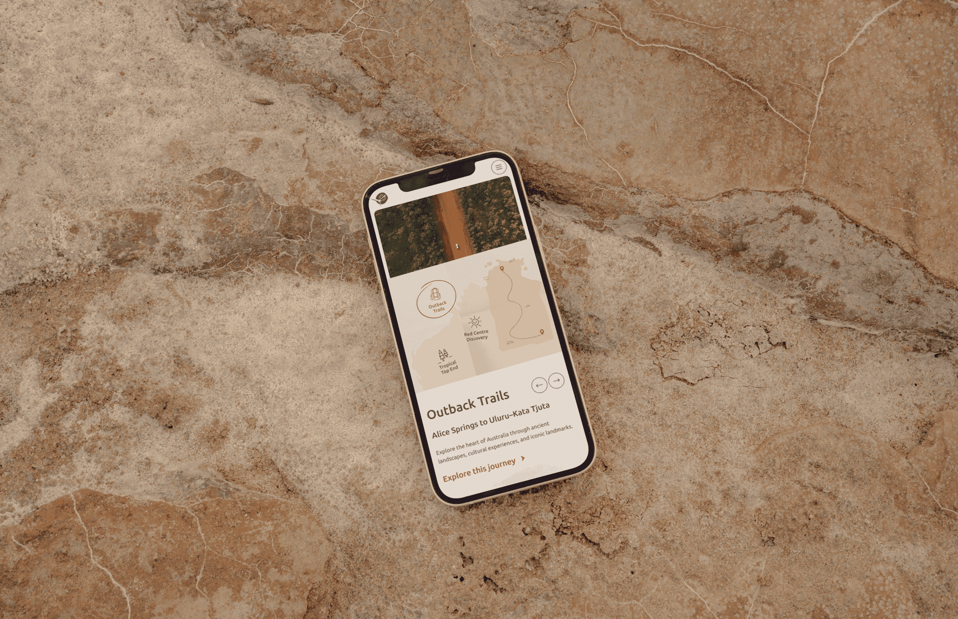 A mock-up of the 'NT Tourism' trail map on a phone lying on rocks.