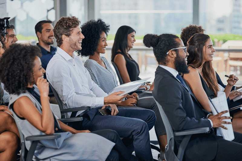 Eine Gruppe von Menschen in Arbeitskleidung sitzt bei einem Seminar.