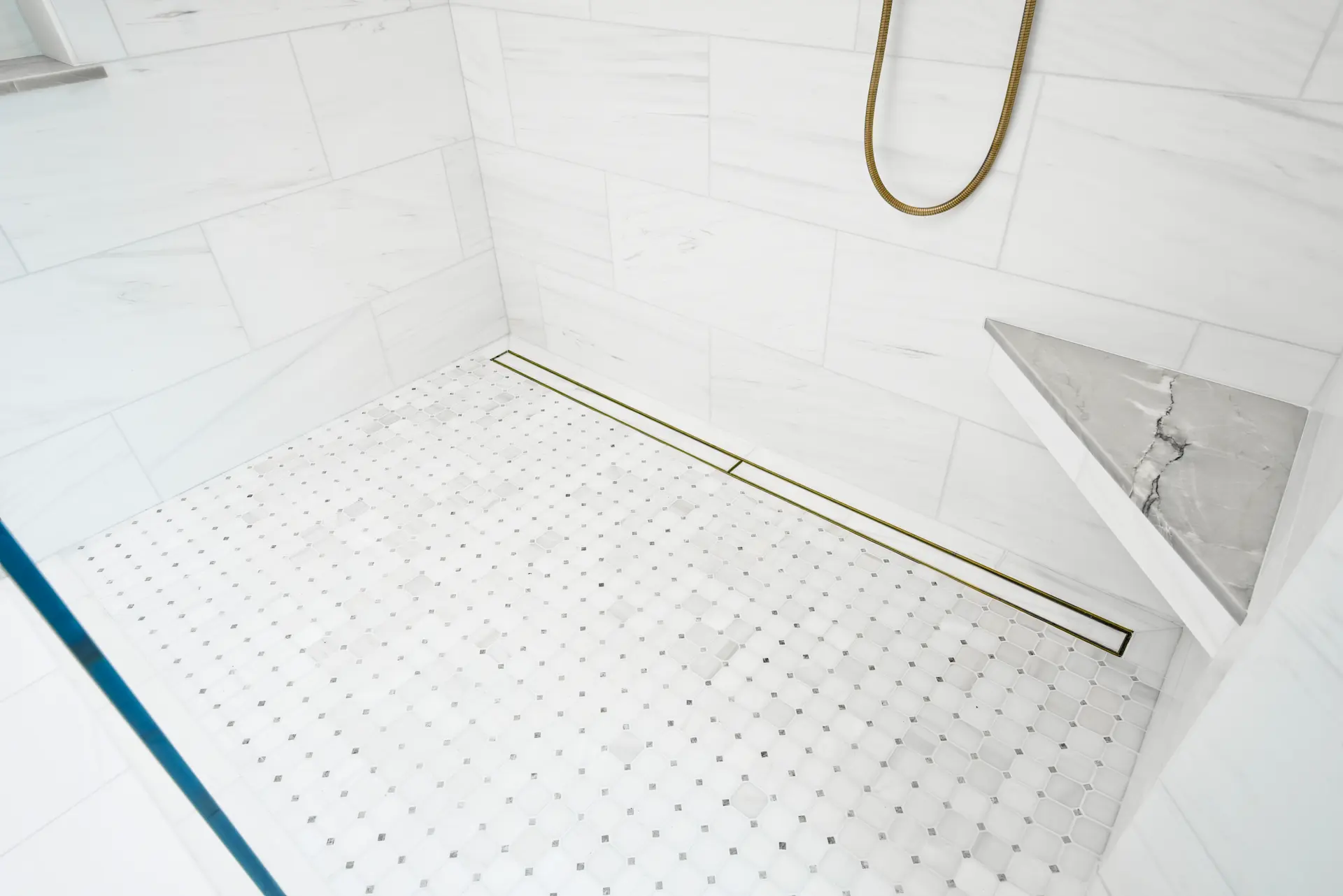 Close-up of the primary bathroom's shower pan featuring a modern linear drain, highlighting the meticulous attention to detail and sophisticated design choices in the Dana Point Full Remodel. Photo by Todd Huge.