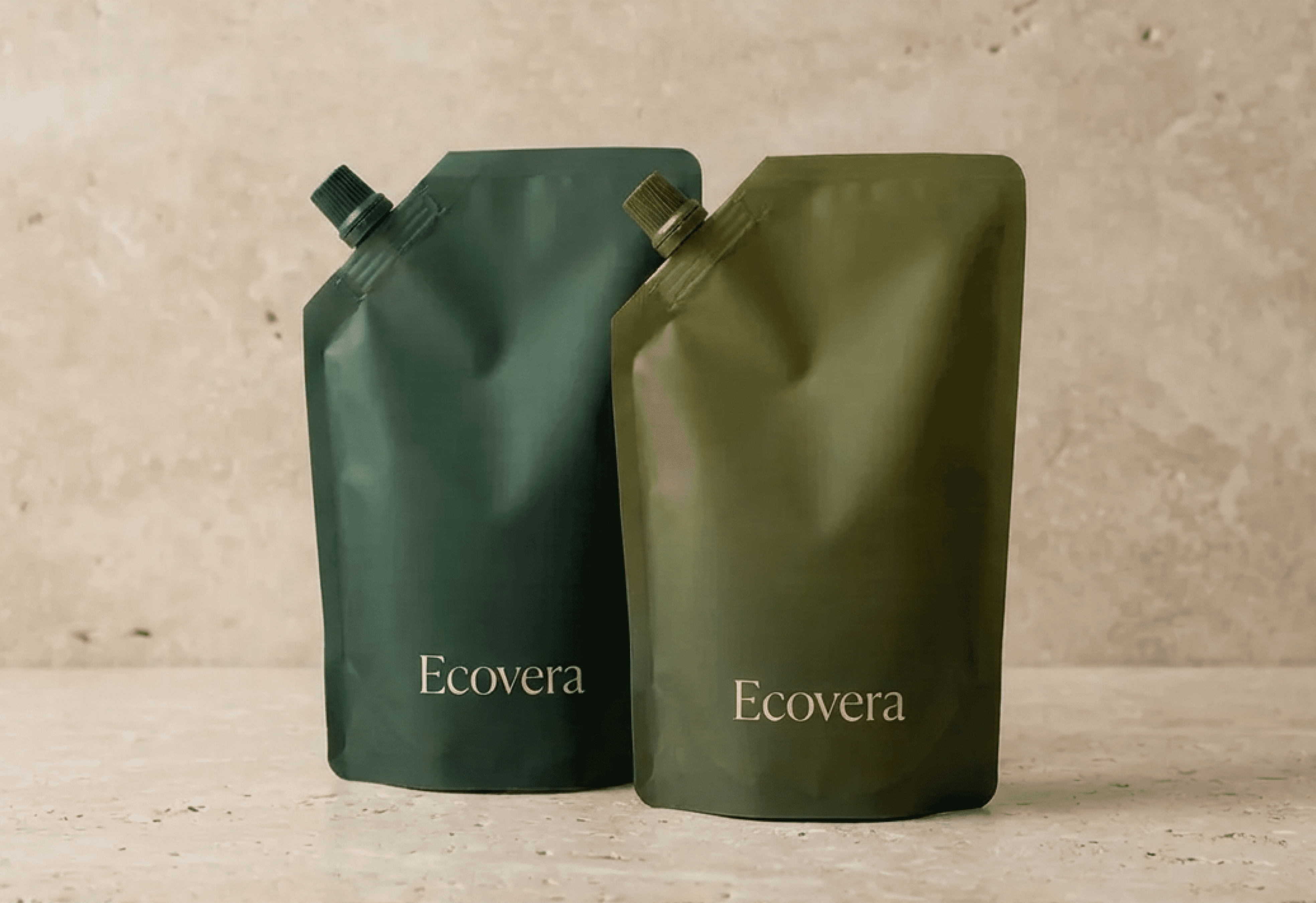Two green Ecovera refillable pouches on a stone surface.