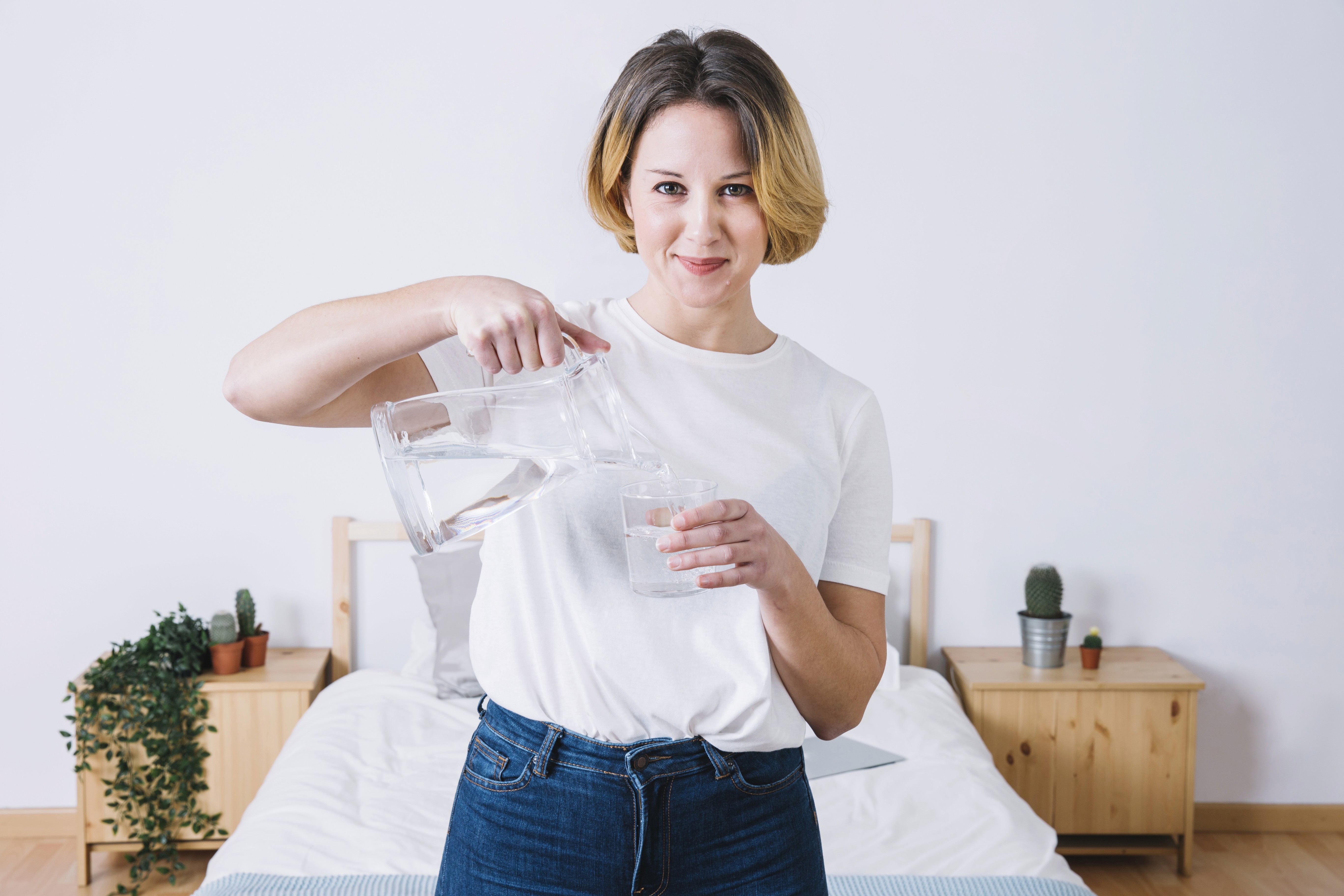A pretty woman pouring water from jug to glass